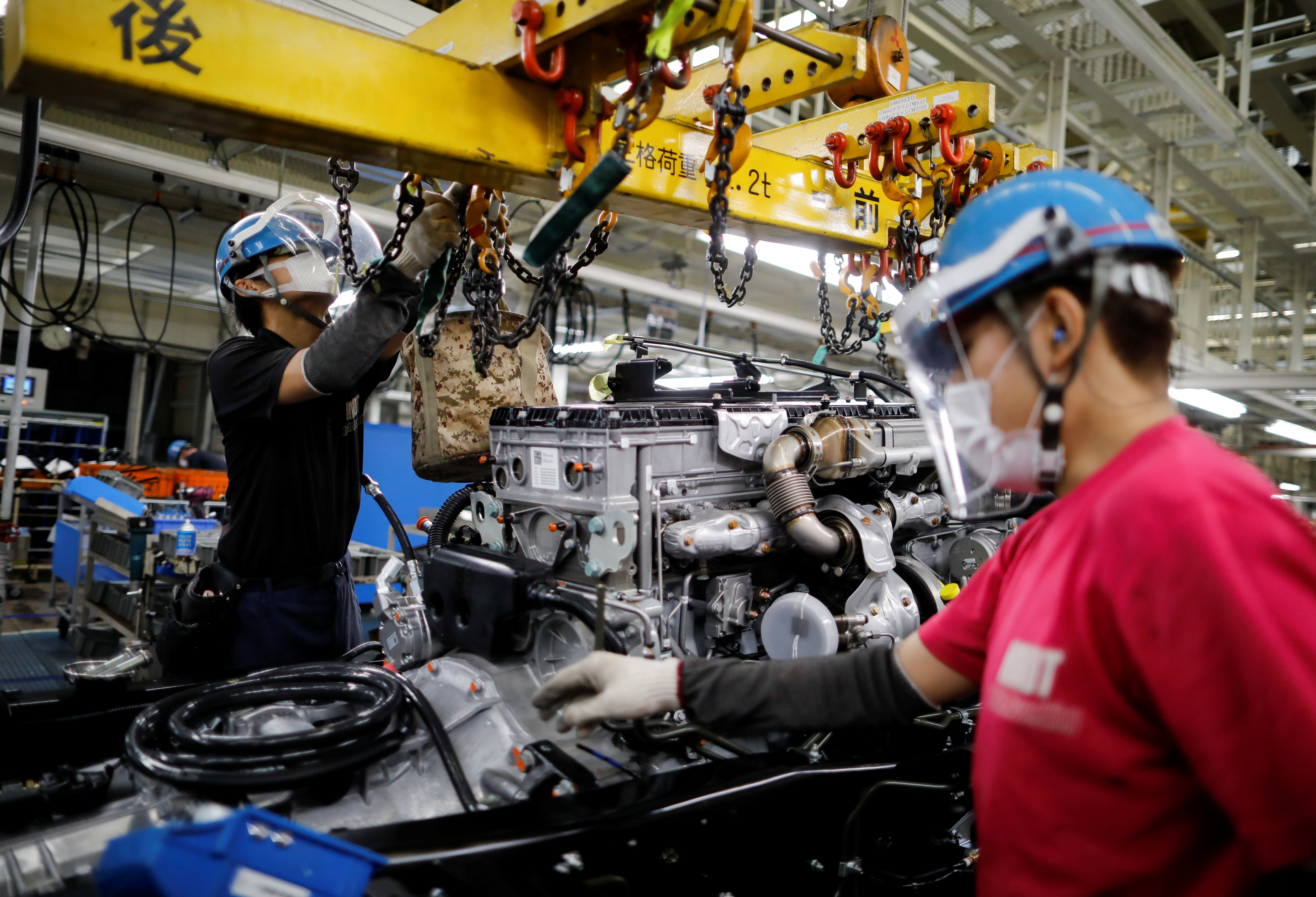 Employees wearing protective face masks and face guards work on the automobile assembly line during the outbreak of the coronavirus disease (COVID-19) at the Kawasaki factory of Mitsubishi Fuso Truck and Bus Corp. in Kawasaki, Japan