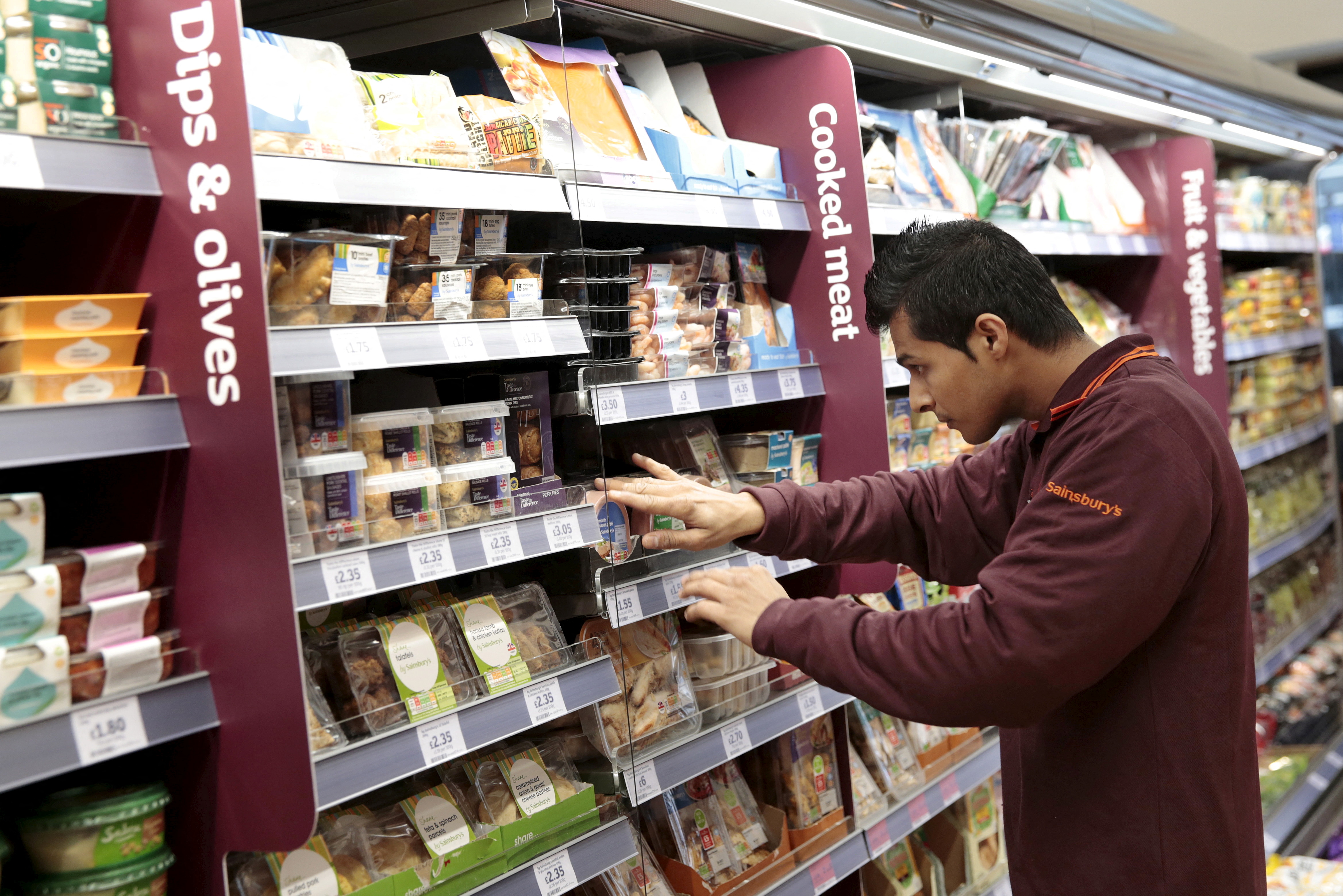 An employee stocks a shelf at a Sainsbury's Local store in central London