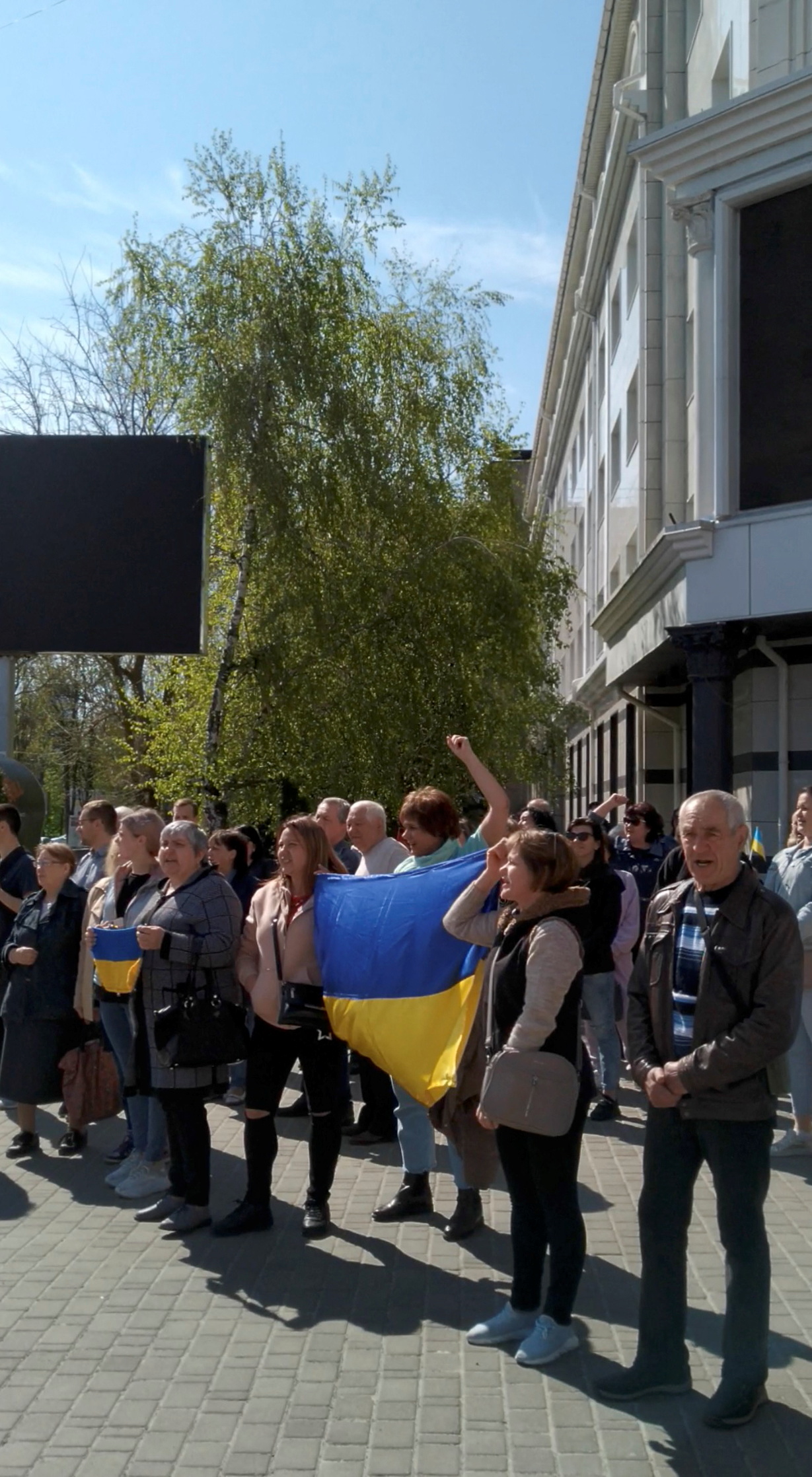 People shout slogans and hold Ukraine's national flag during a protest where tear gas was fired on them, amid Russia's invasion of Ukraine, in Kherson