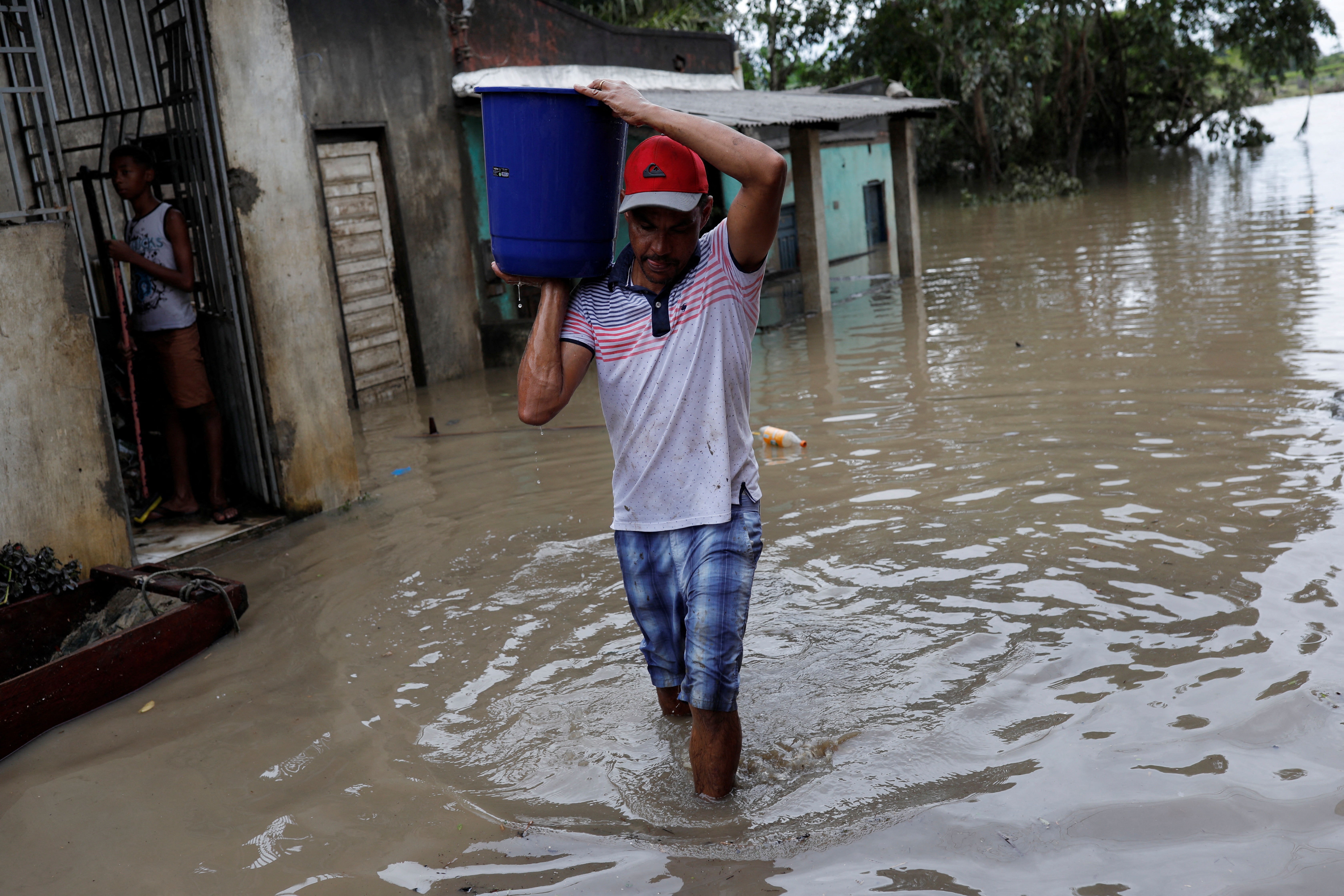A man carries a bucket of water, during floods caused due to heavy rains, in Itabuna, Bahia state, Brazil December 27, 2021. REUTERS/Amanda Perobelli