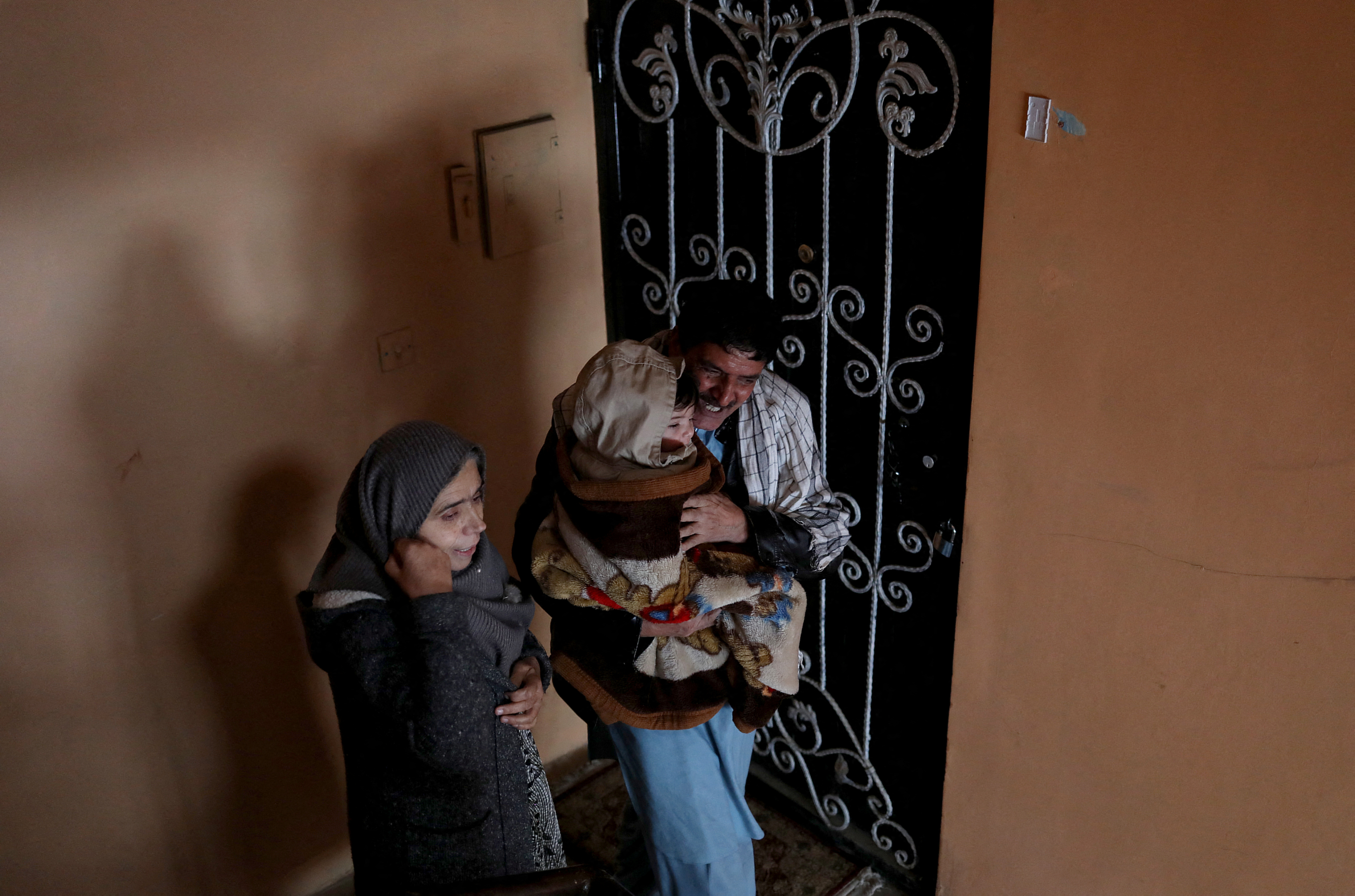 Baby Sohail Ahmadi is carried by a relative as they leave the house of Hamid Safi in Kabu