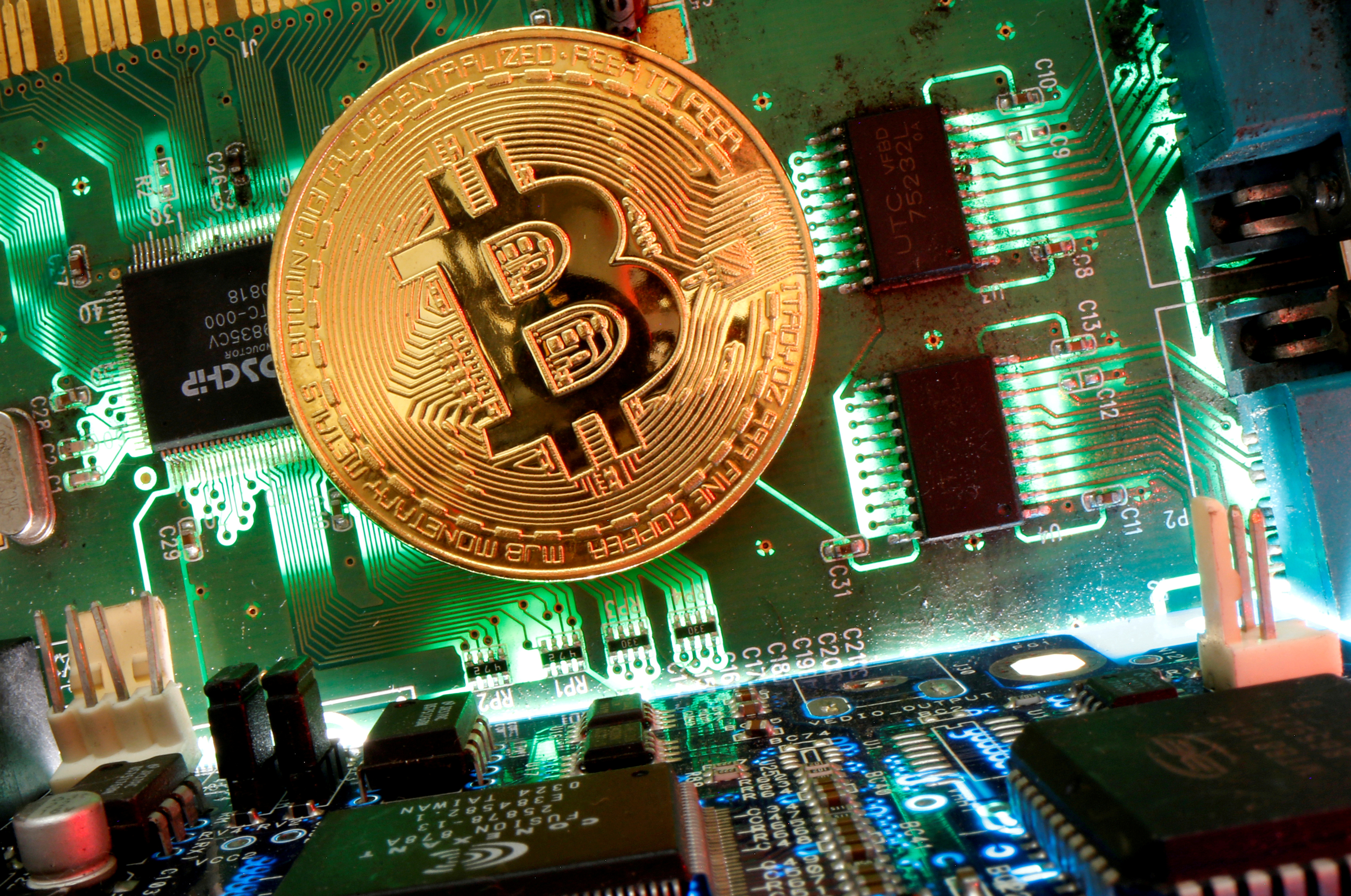 Representation of the virtual currency Bitcoin is seen on a motherboard in this picture illustration