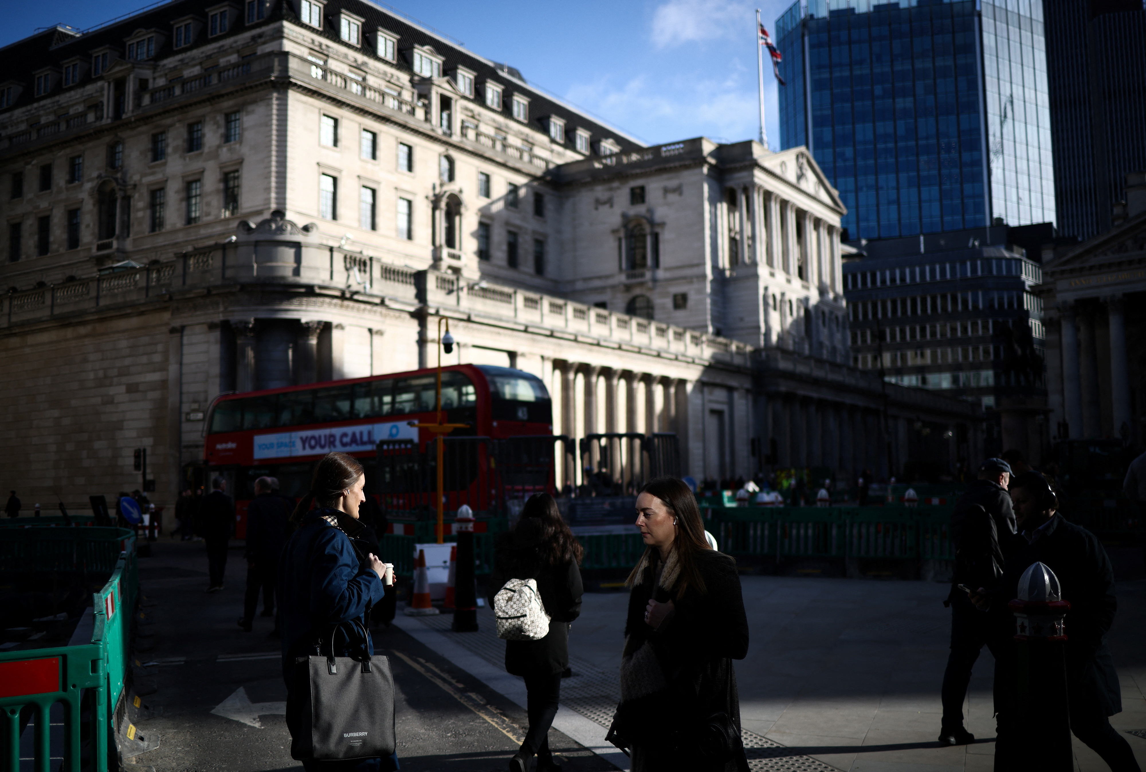 People walk outside the Bank of England in the City of London financial district in London