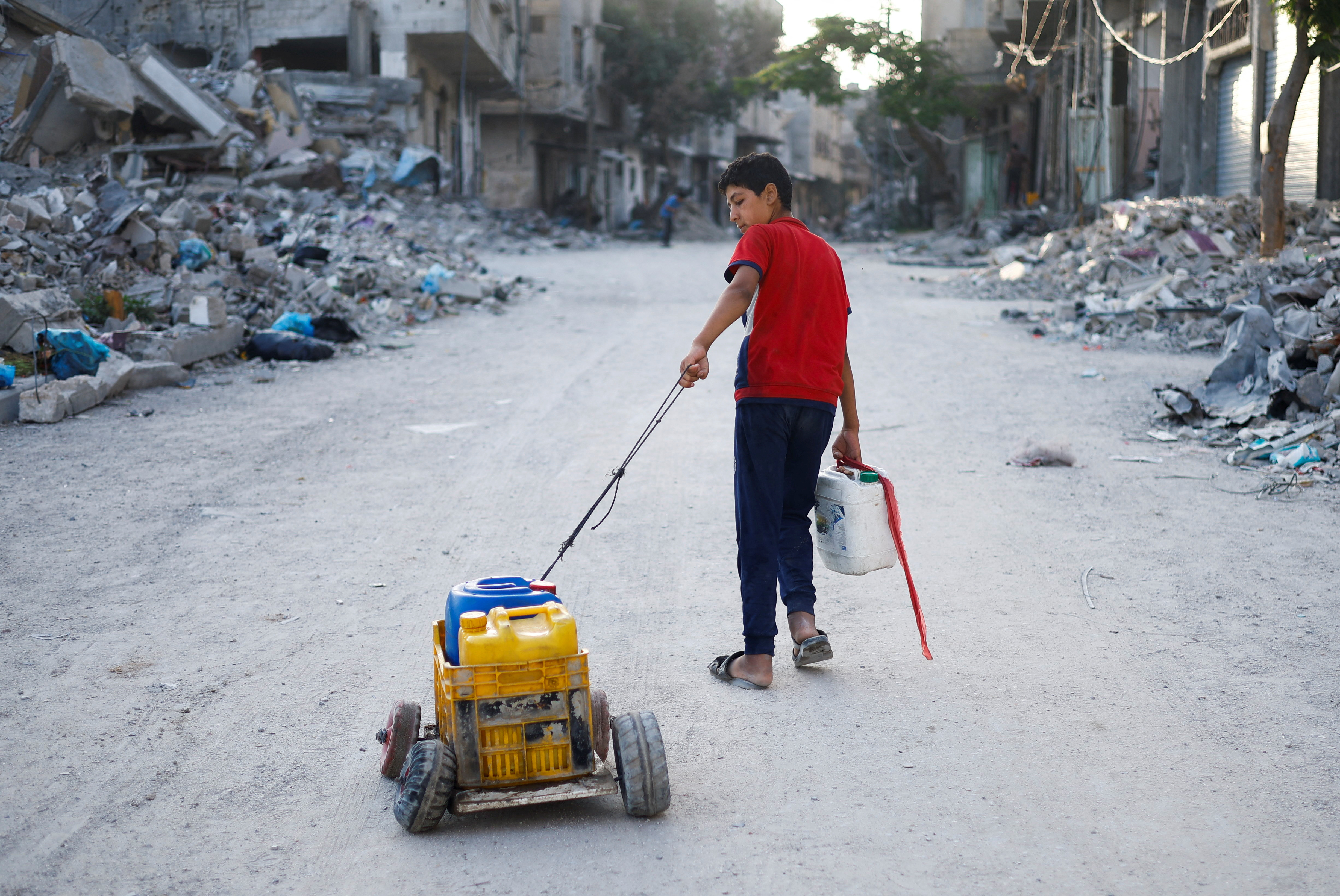 A Palestinian child pulls water containers, amid the ongoing conflict between Israel and Hamas, in southern Gaza City, in the Gaza Strip