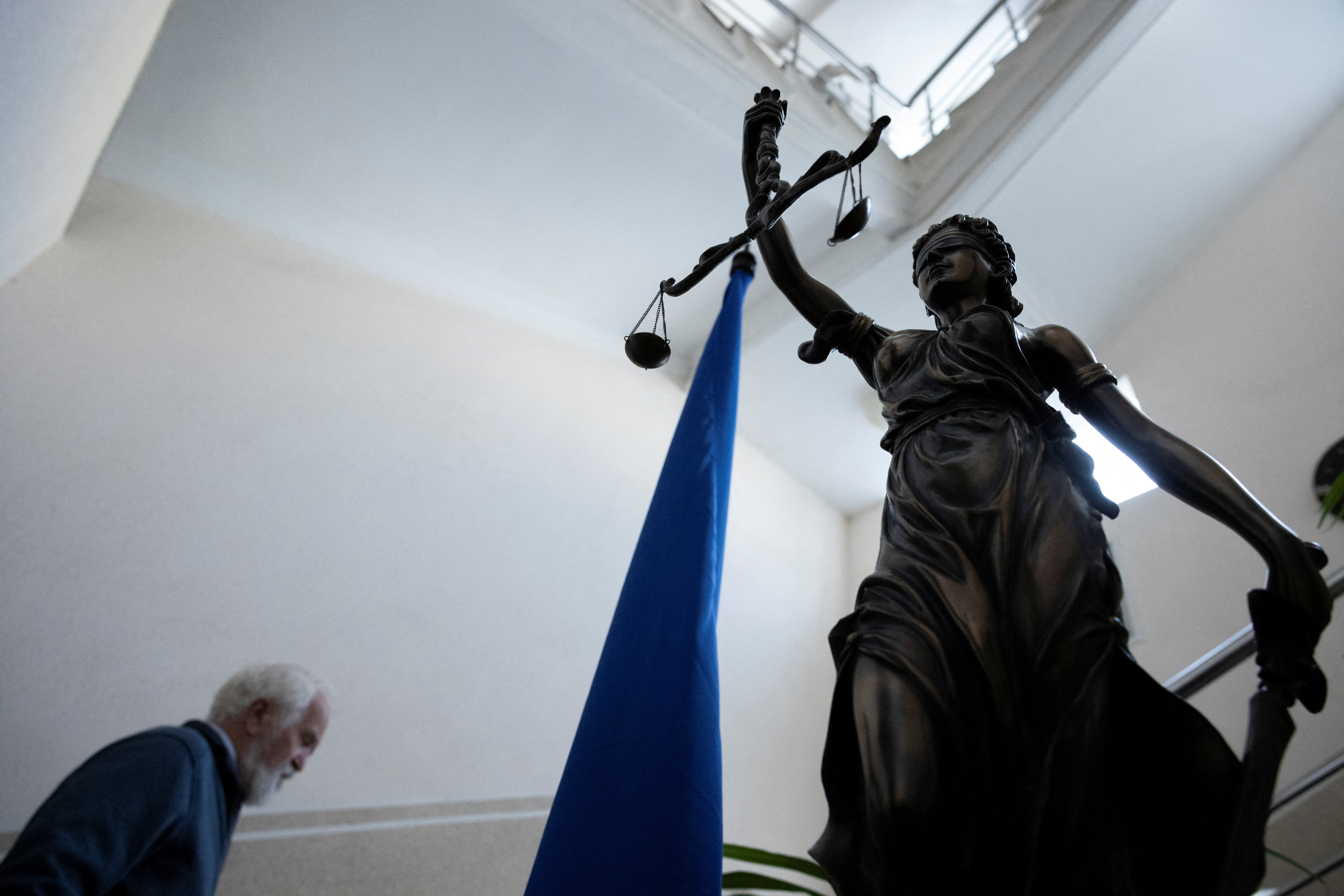 A man walks past a statue of Lady Justice as he arrives at the Pecherskyi District Court of Kyiv City in Kyiv