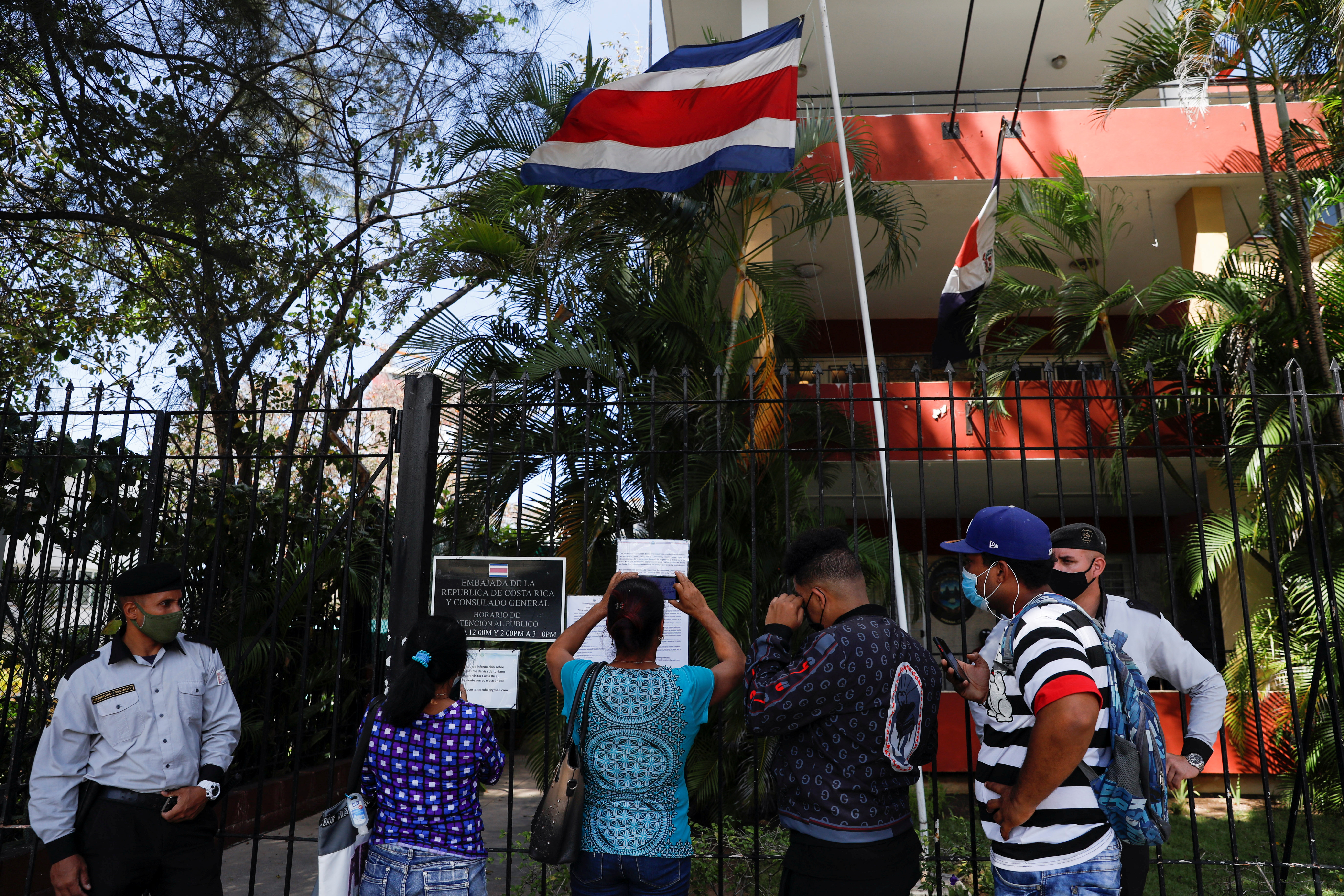 People take pictures using their mobile phones of a list with visa requirements for Cubans in front of the Costa Rica embassy, in Havana