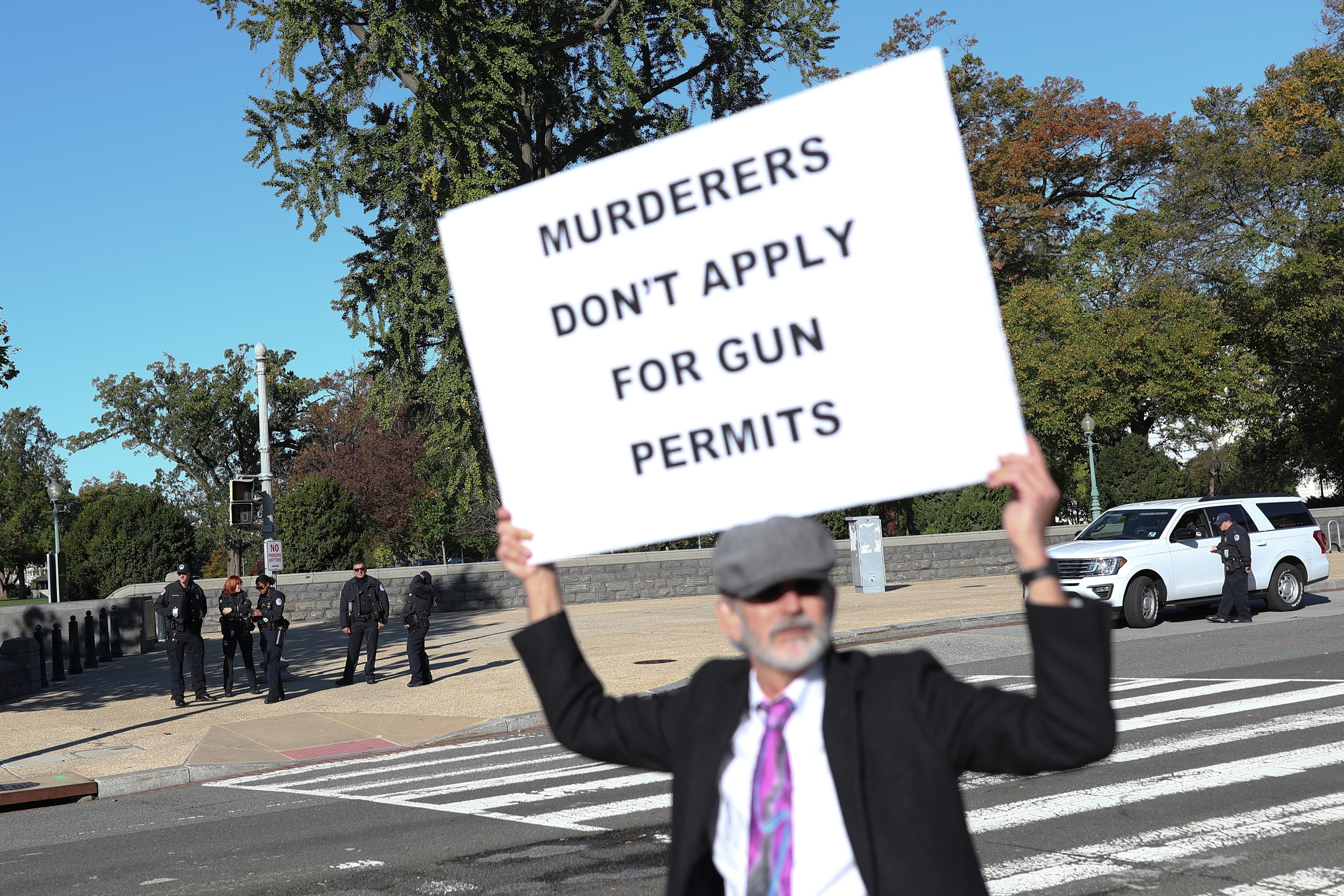 Perry Sharpeless walks along First Street while displaying a sign of protest during a demonstration at the U.S. Supreme Court in Washington, U.S., November 3, 2021. REUTERS/Tom Brenner