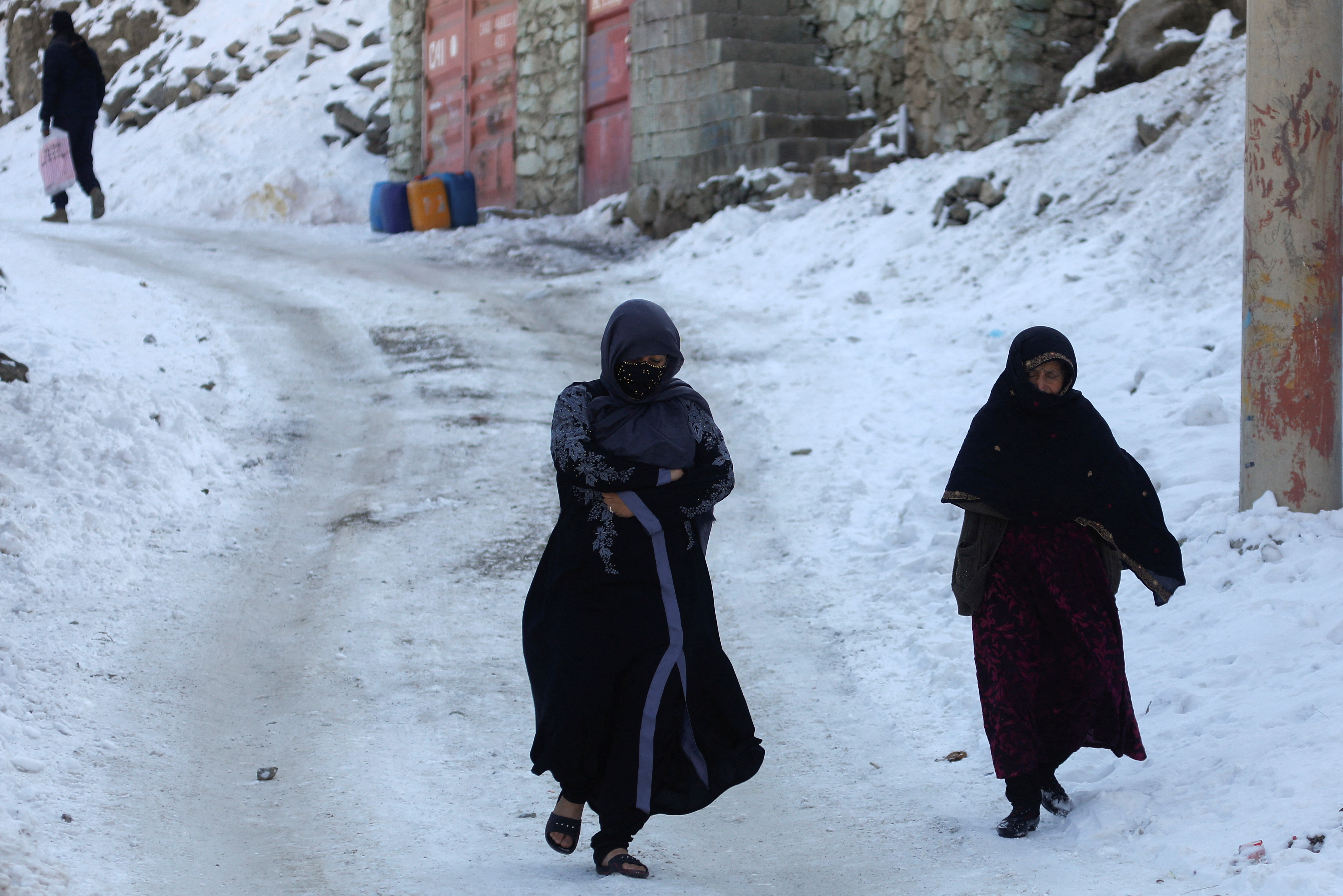 Two women walk on a snow-covered street on the TV mountain in Kabul