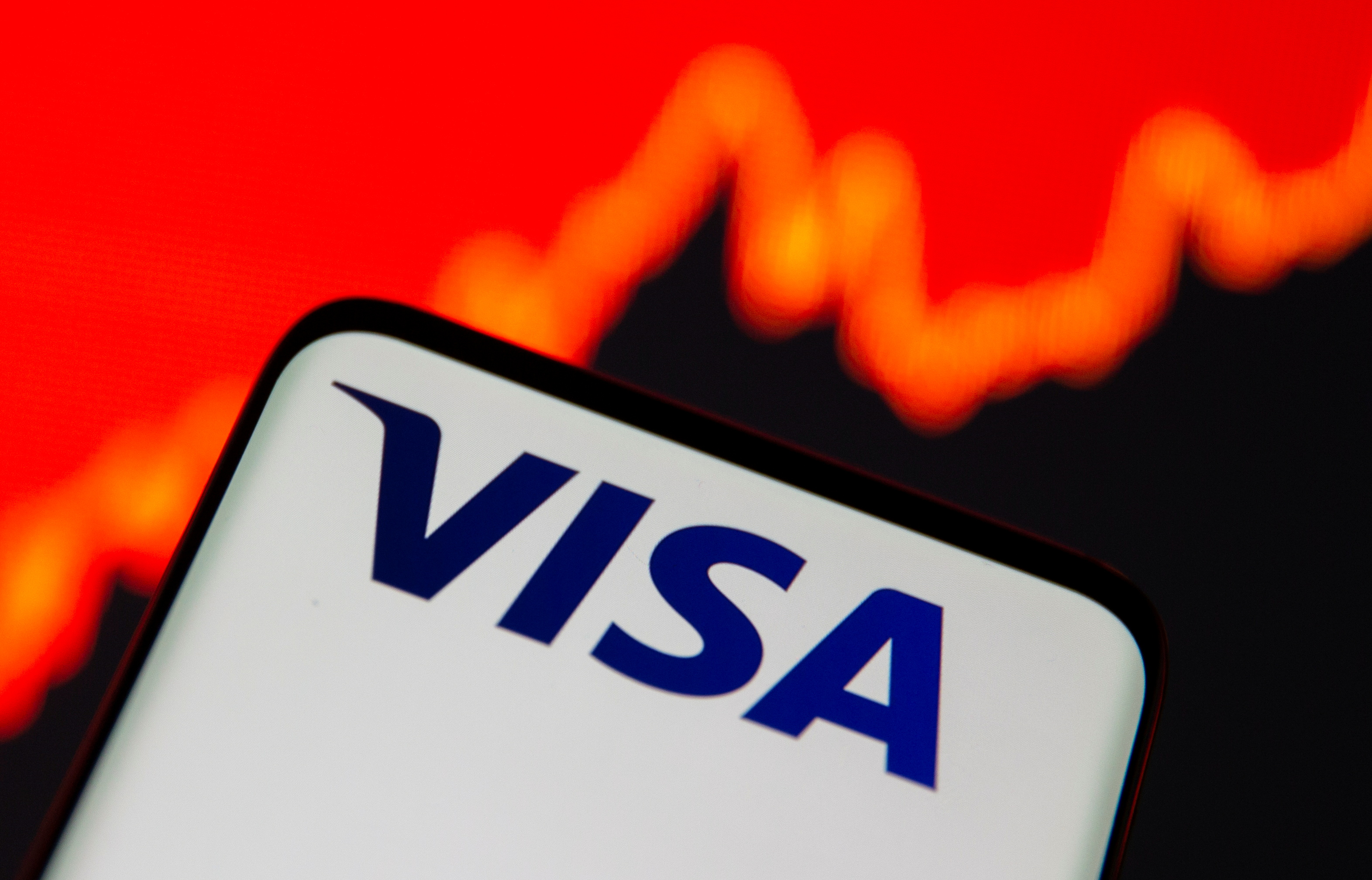 Smartphone with Visa logo is seen in front of displayed stock graph in this illustration