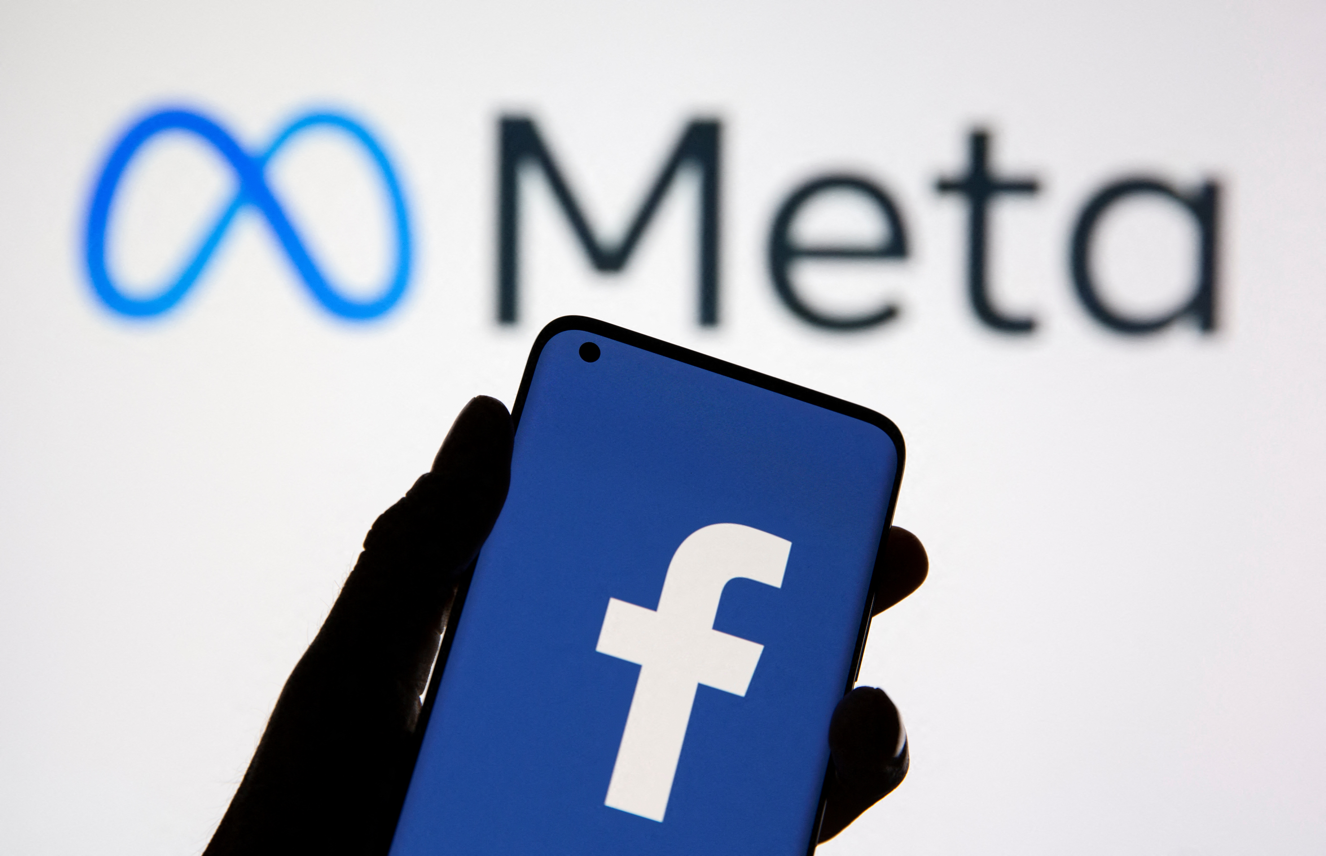 Un teléfono inteligente con el logotipo de Facebook es un lago frente al nuevo meta del logotipo de cambio de marca de Facebook que se muestra en esta ilustración