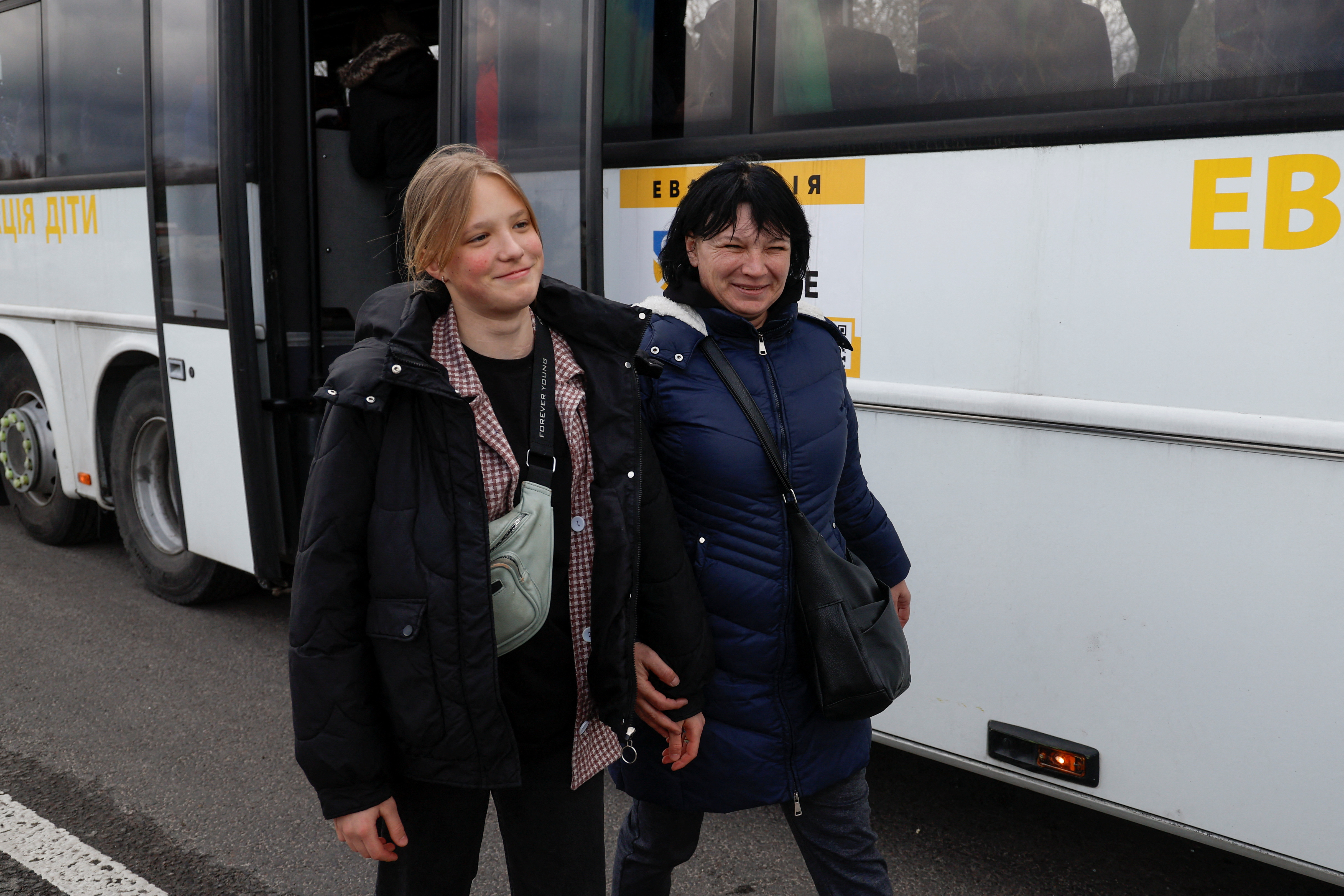 Natalia Rakk smiles as she walks with her 14-year-old daughter Aliona, taken to Russia, after returning via the Ukraine-Belarus border, in Volyn region