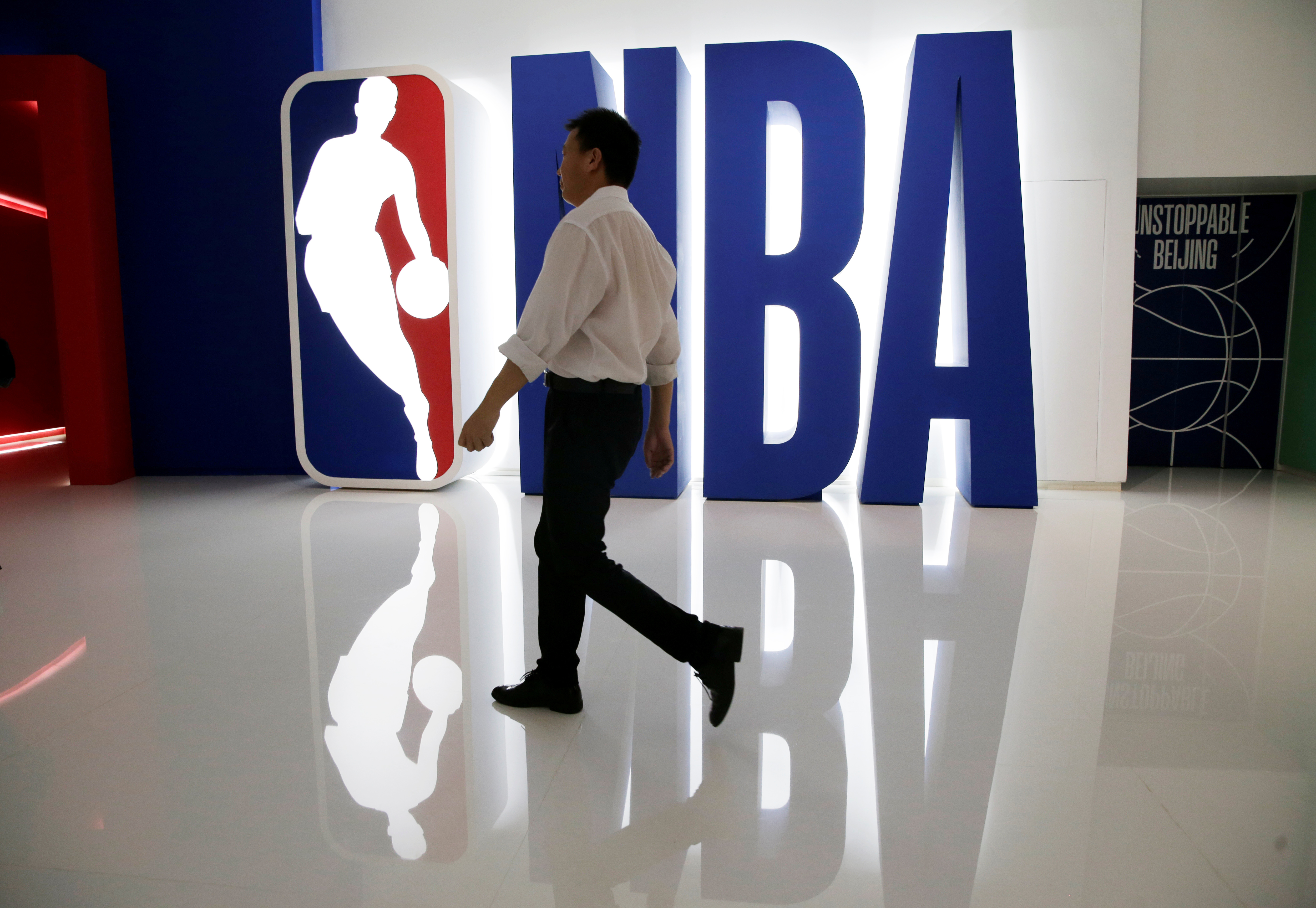 A man walks past an NBA logo at an NBA exhibition in Beijing
