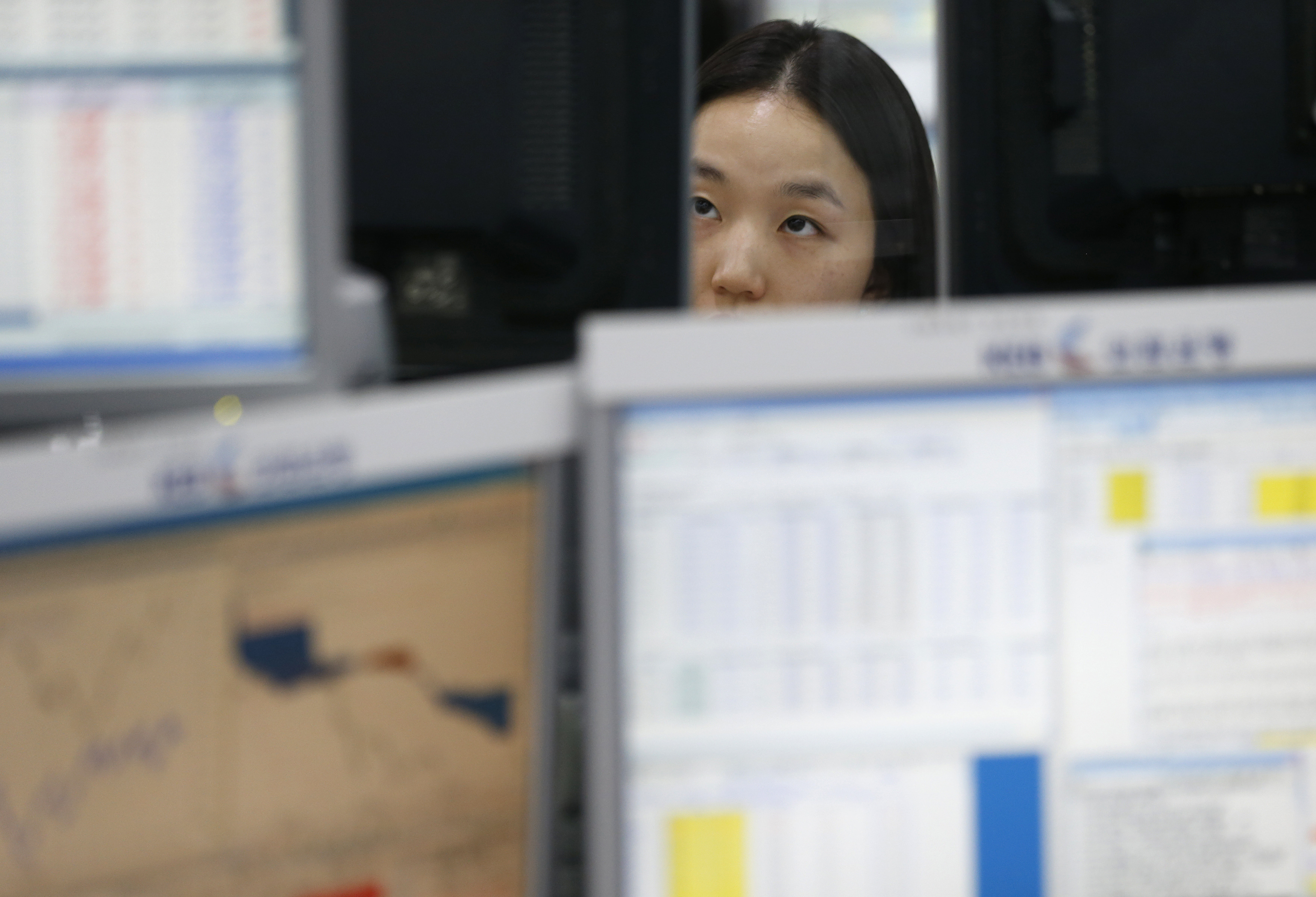 A currency dealer looks at screens at a dealing room of a bank in Seoul