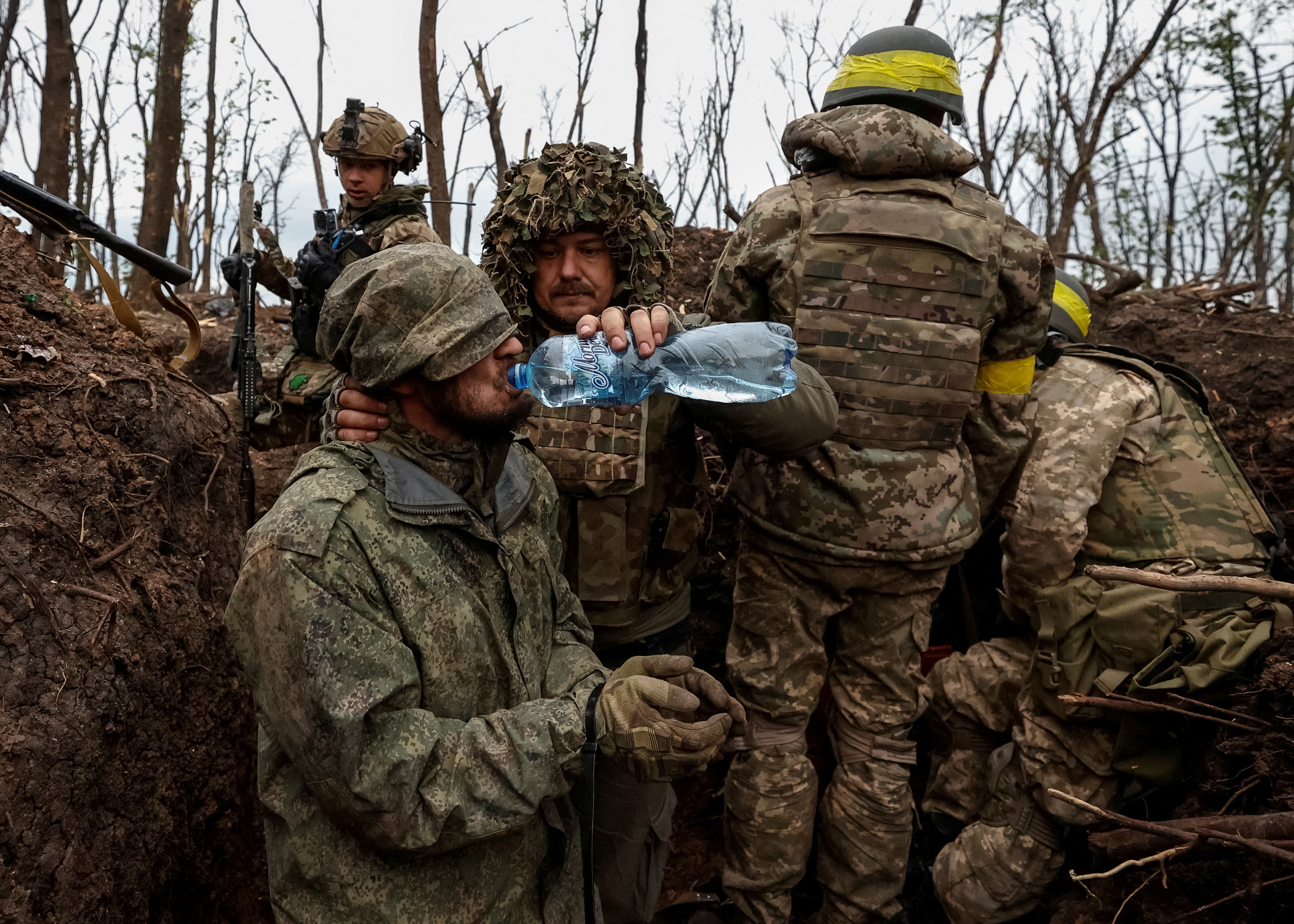 A Ukrainian soldier gives water to captured Russian soldiers near the front-line city of Bakhmut.