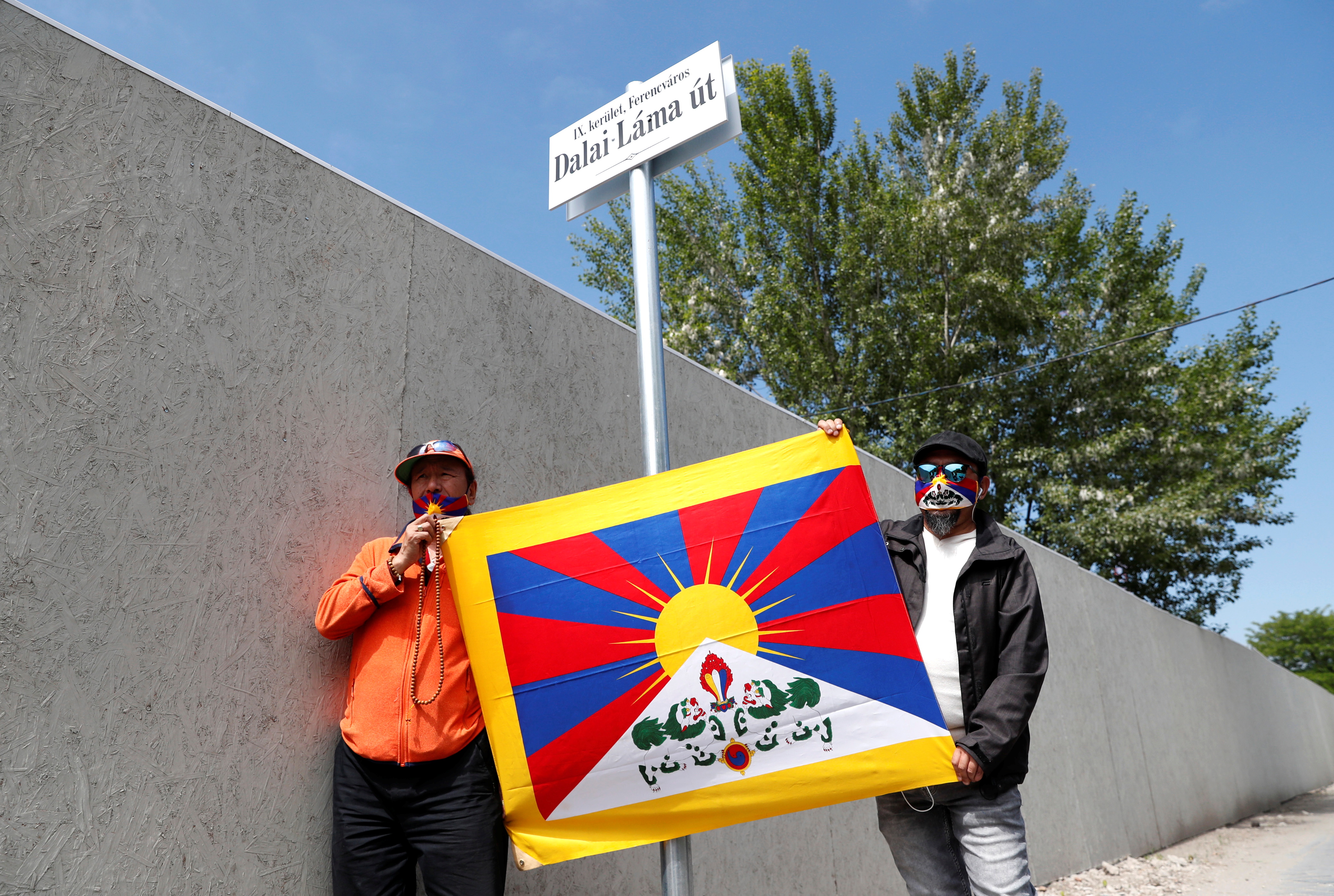 Activists hold a Tibetan flag next to a sign in a street renamed 'Dalai Lama', near the planned site of the campus of Chinese Fudan University in Budapest