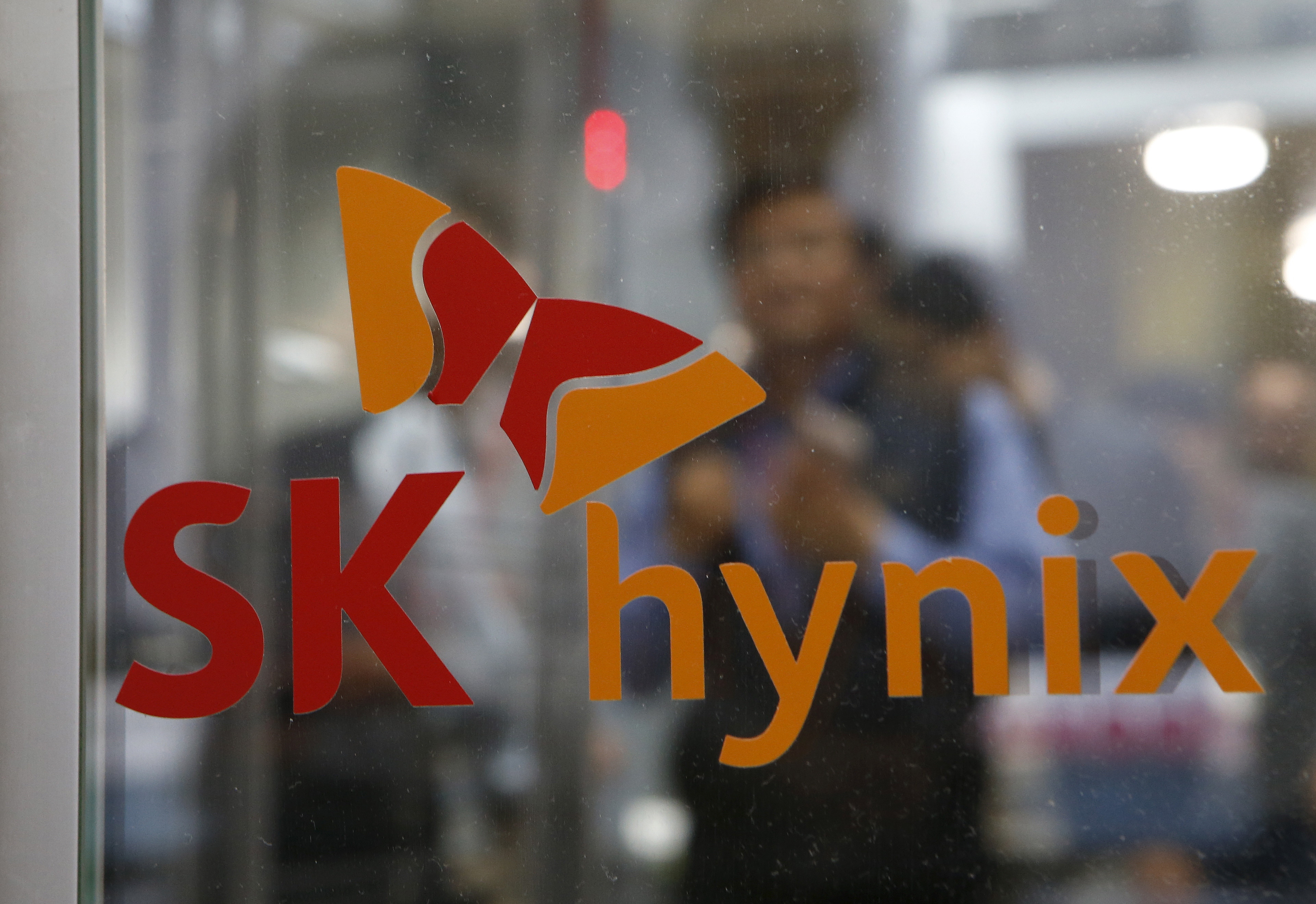 Employee walk past the logo of SK Hynix at its headquarters in Seongnam