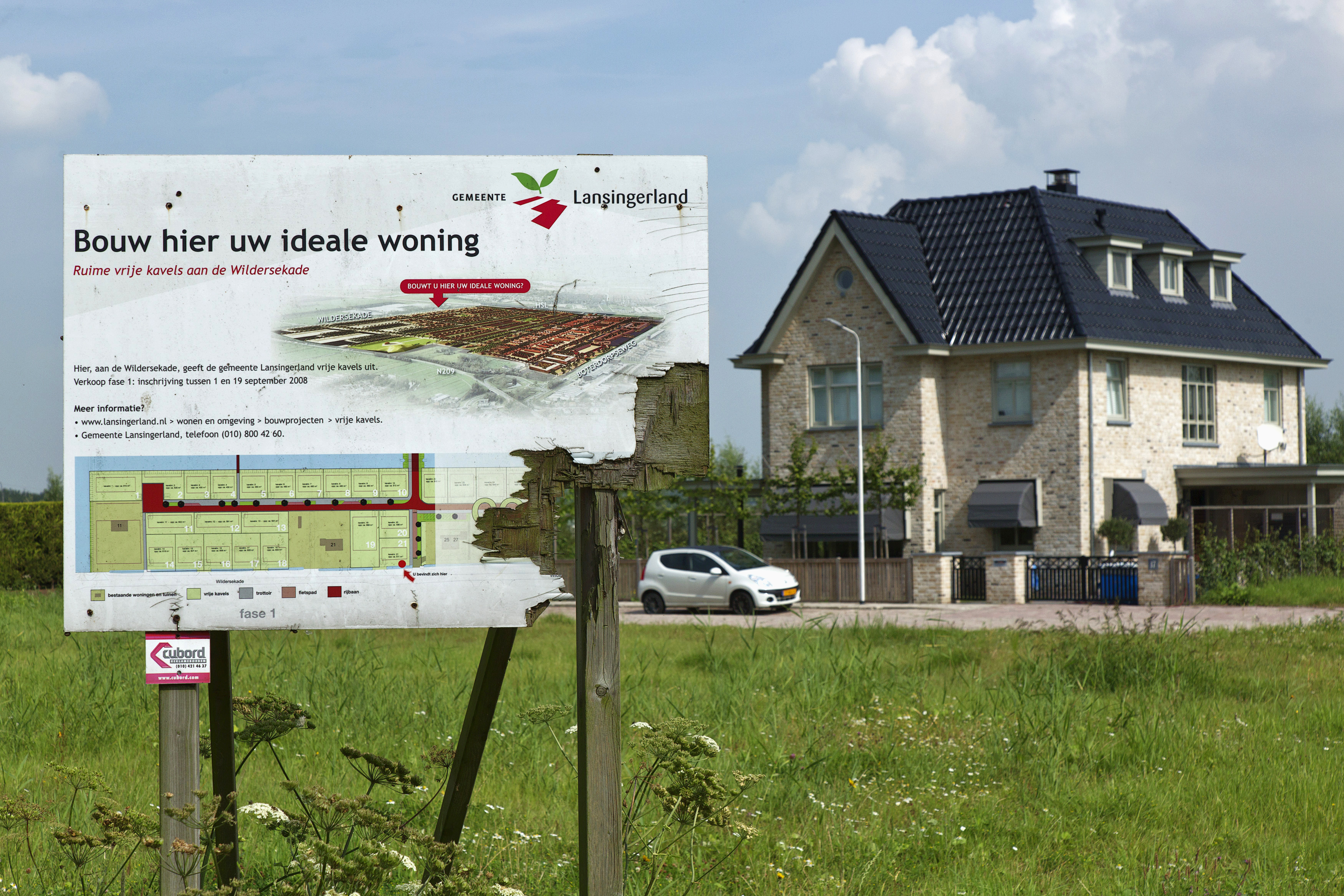 Weathered wooden sign advertising new luxury housing is seen in Lansingerland