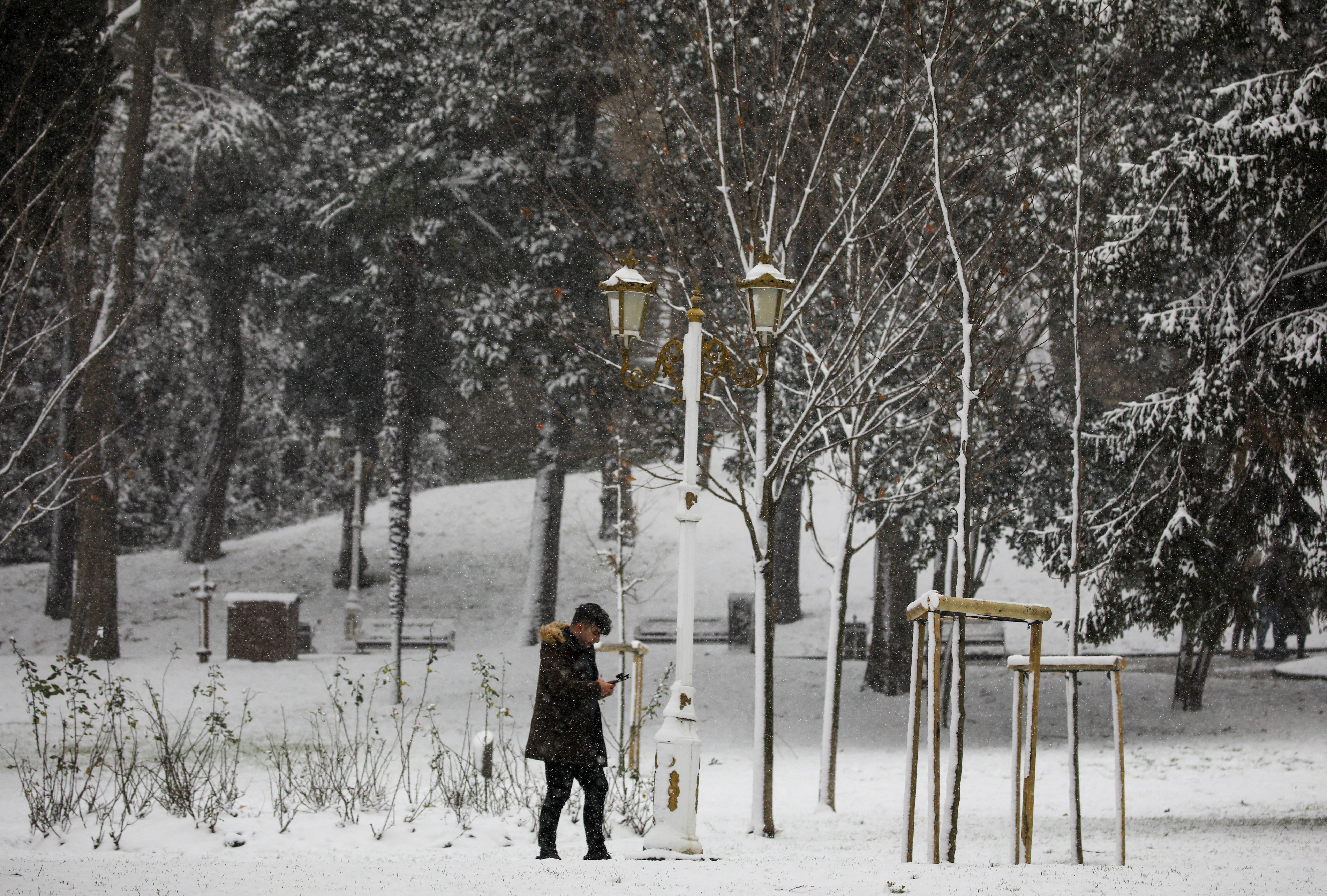 A man walks along a park on a snowy day in Istanbul