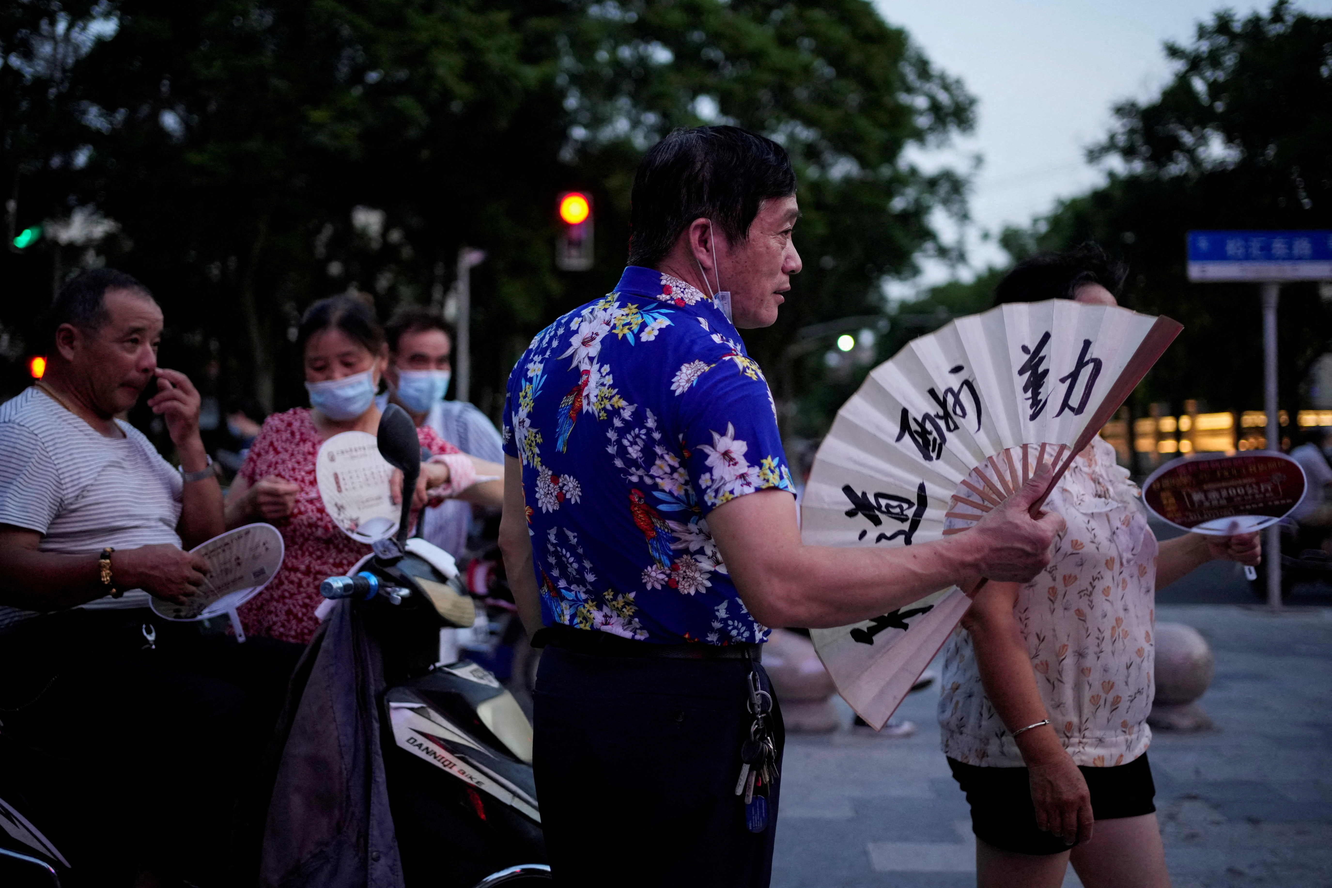People use fans as they gather in a park amid a heatwave warning in Shanghai, China