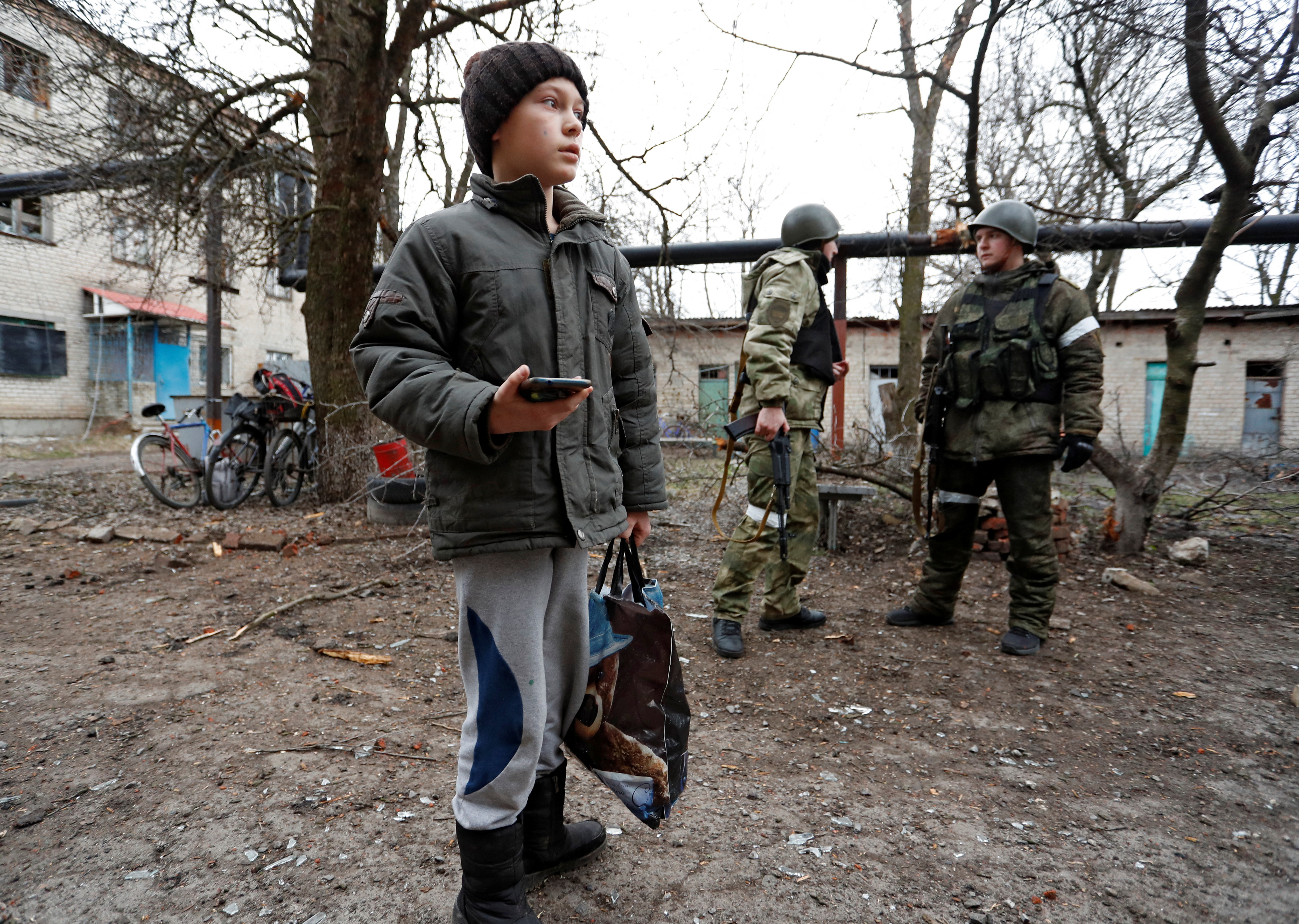 A boy stands in front of an apartment building, which locals said was damaged by recent shelling, in Yasynuvata