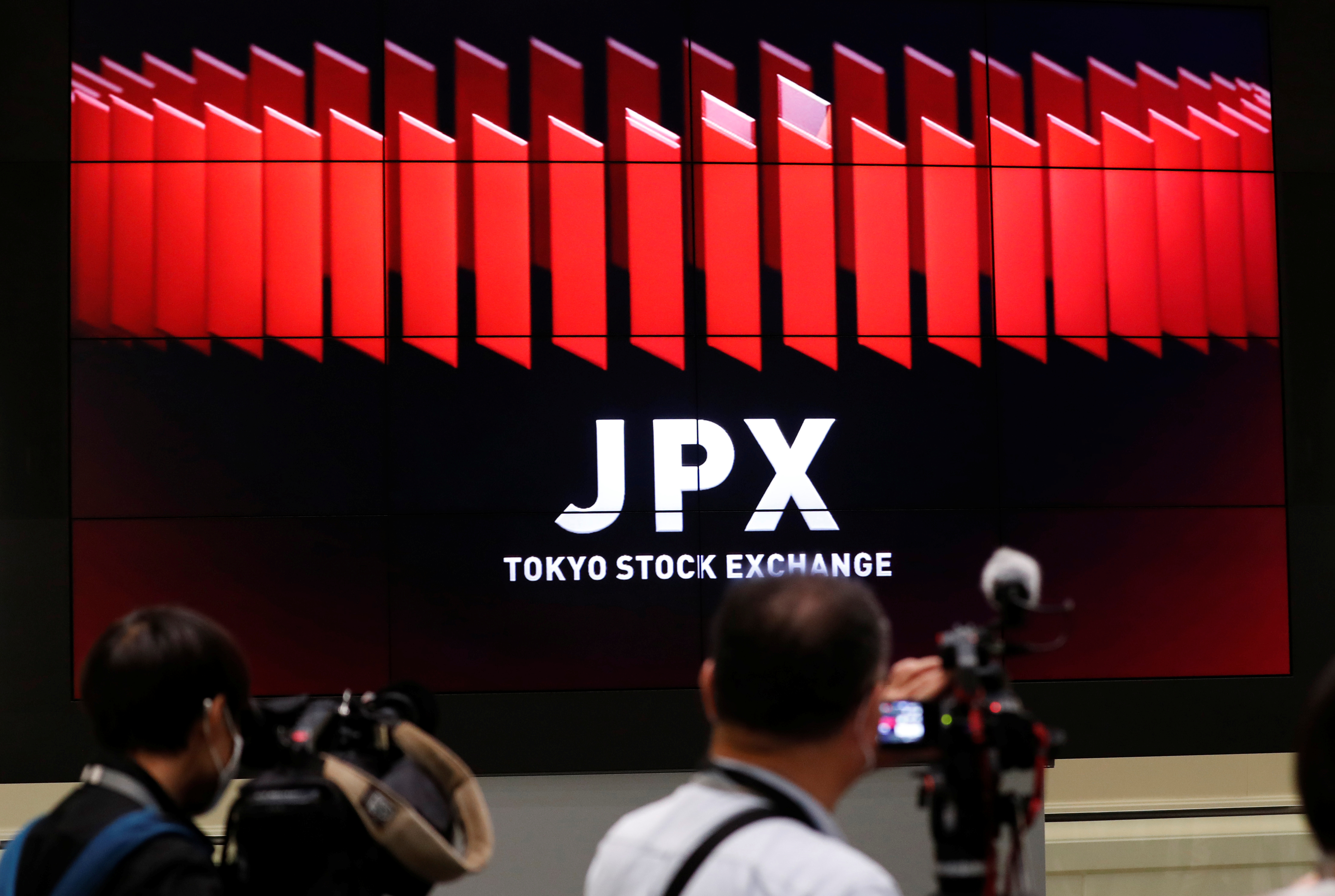 TV camera men wait for the opening of market in front of a large screen showing stock prices at the Tokyo Stock Exchange in Tokyo