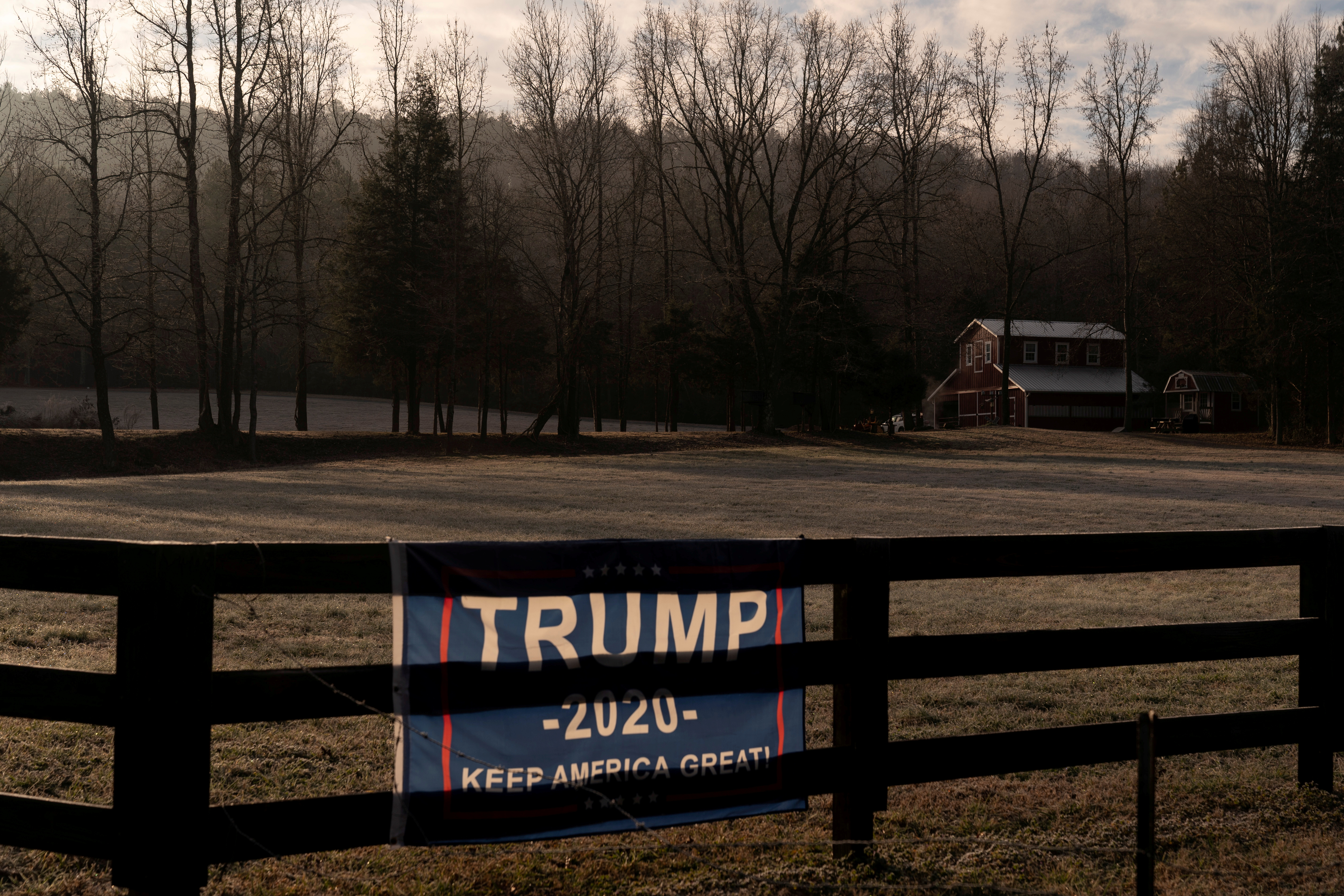 A campaign flag for former president Donald Trump is seen on a fence in front of a barn near Rome