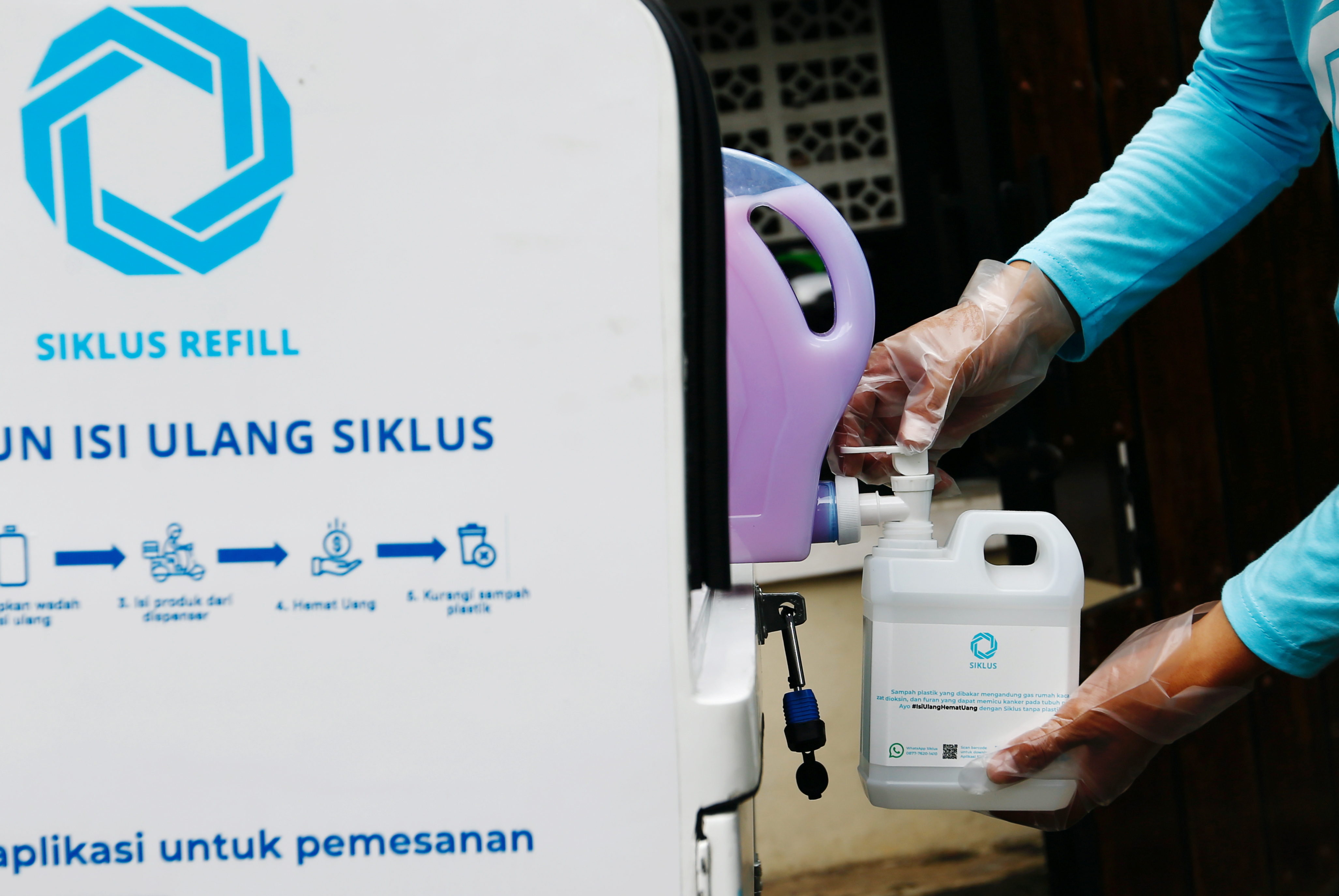 A worker at Siklus, a start-up company which refills household products in a bid to reduce plastic waste, refills a jerry can with cleaning liquid for a customer in Jakarta, Indonesia, May 19, 2021. Picture taken May 19, 2021 REUTERS/Ajeng Dinar Ulfiana