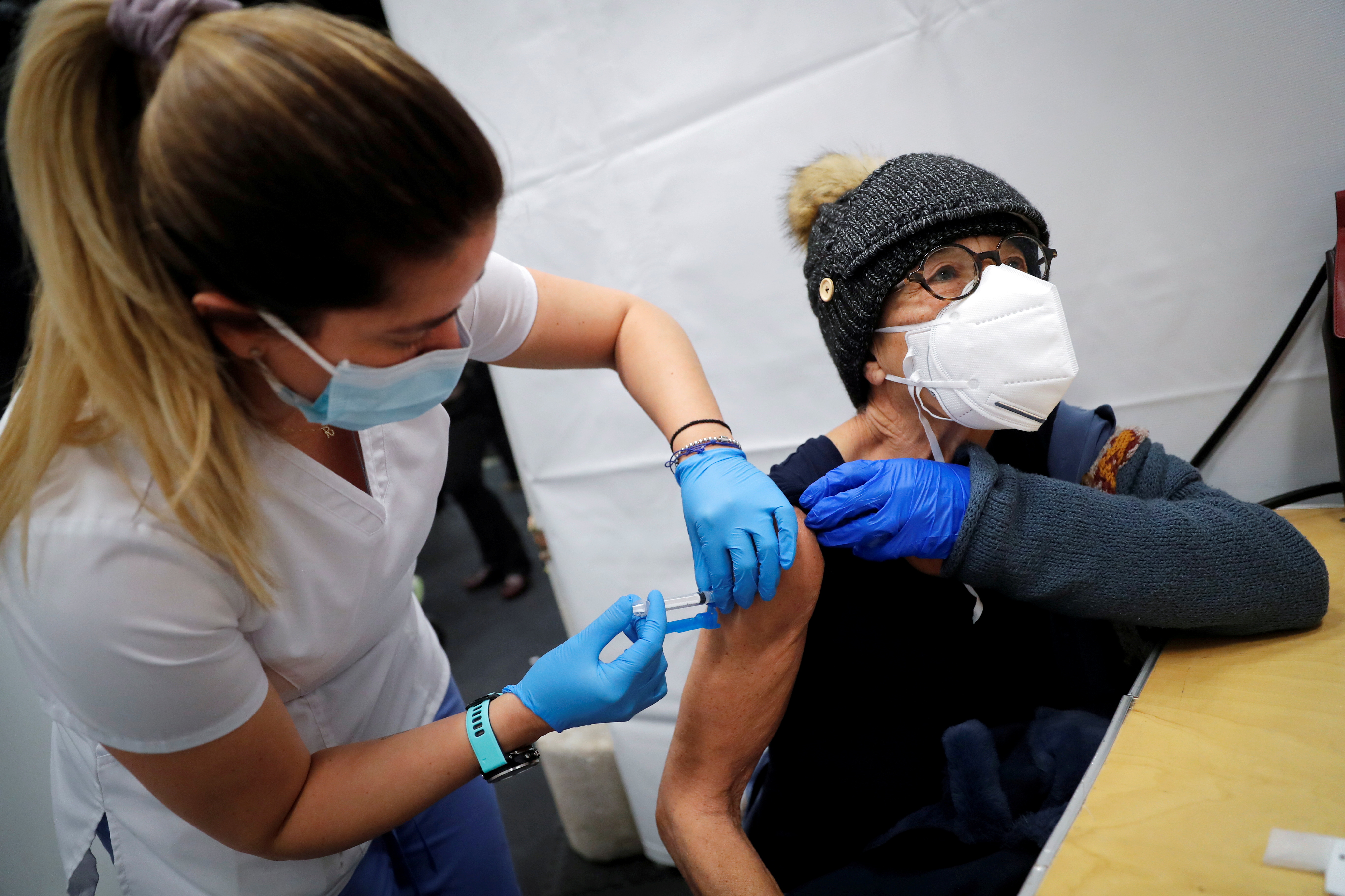 A healthcare worker administers a shot of the Moderna COVID-19 vaccine to a woman at a pop-up vaccination site operated by SOMOS Community Care in Manhattan, Jan. 29, 2021.