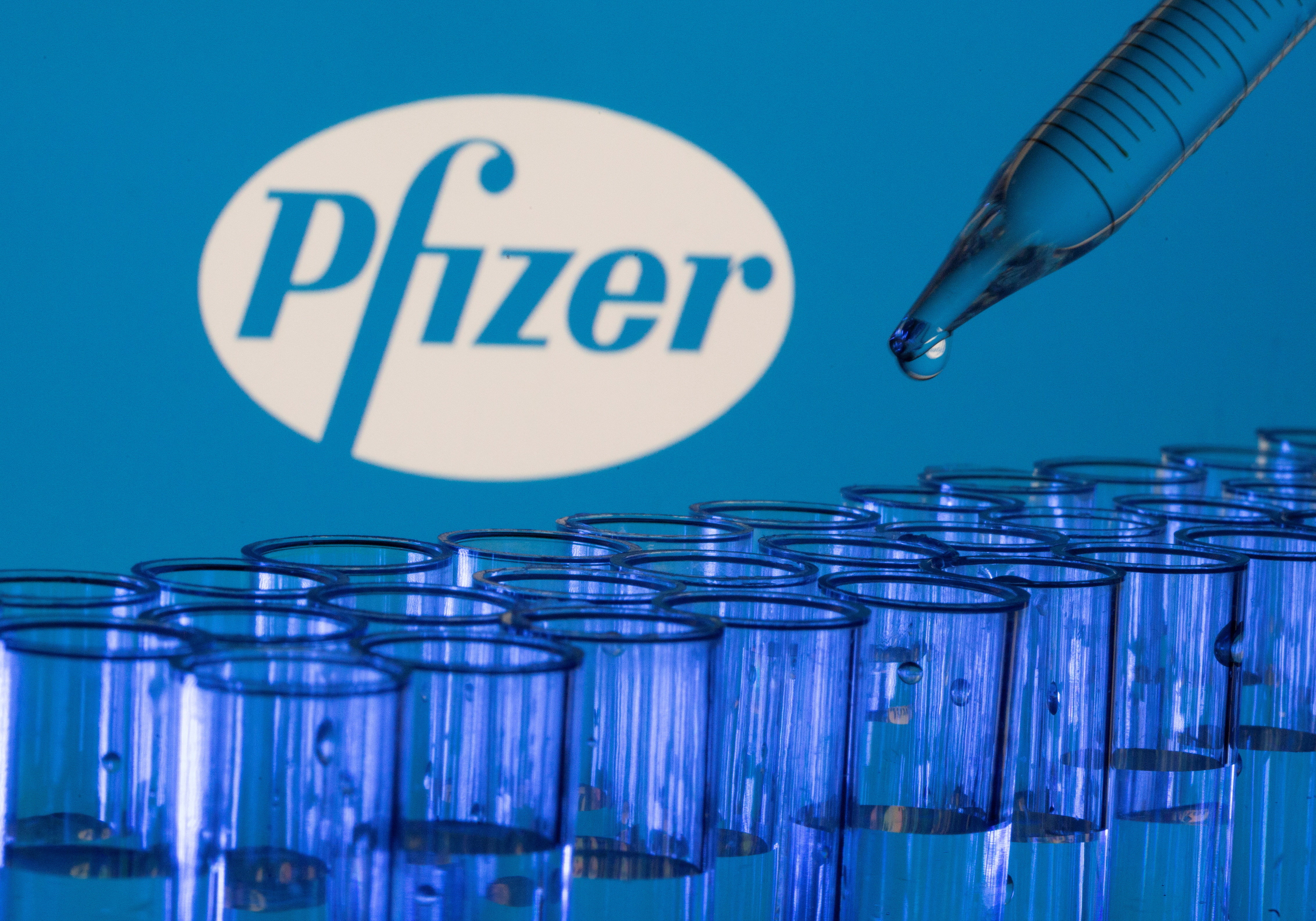 Test tubes are seen in front of  a displayed Pfizer logo in this illustration