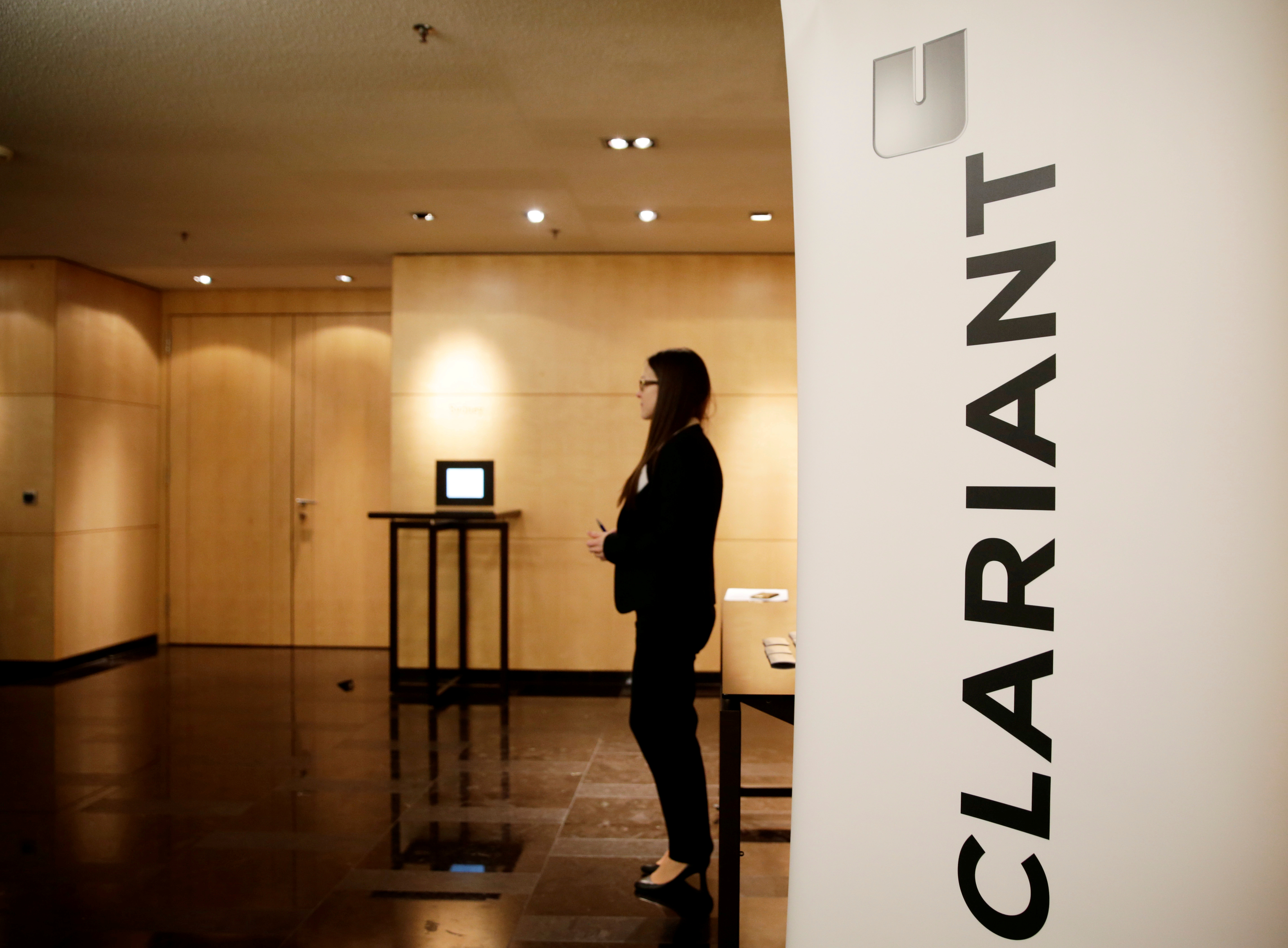 Woman stands next to logo of Swiss specialty chemicals company Clariant ahead of a news conference to present full-year results in Zurich