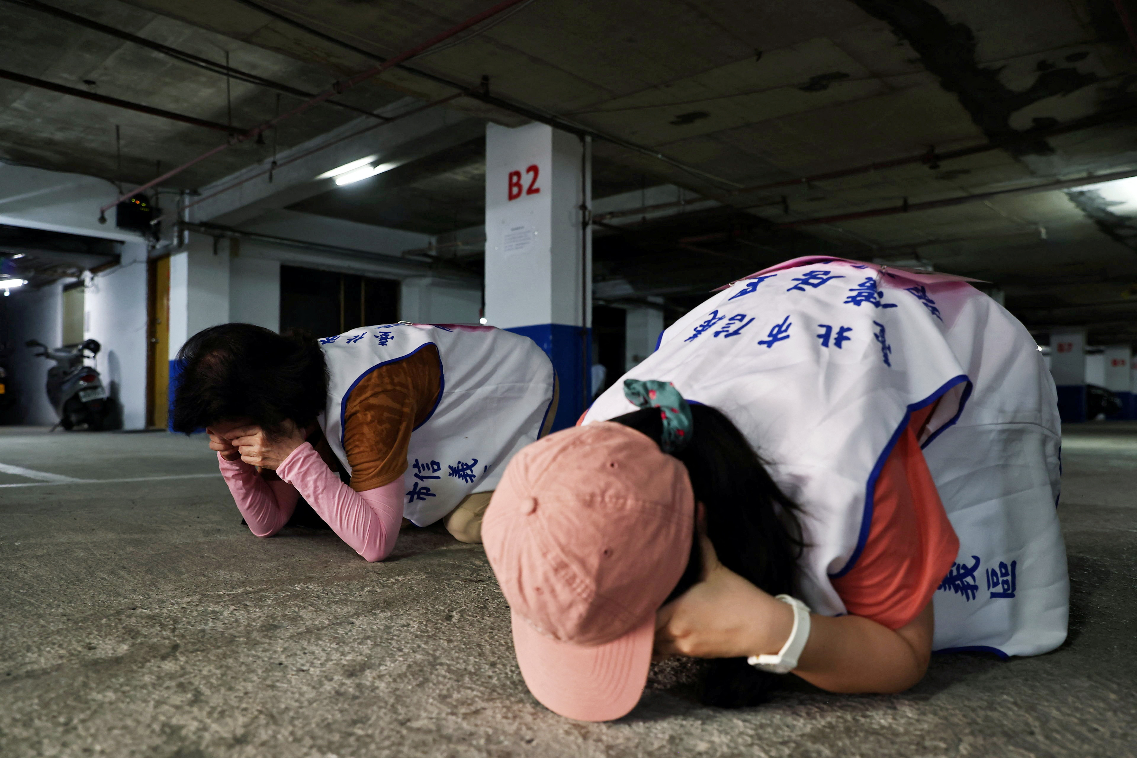 People demonstrate taking shelter during a drill at a basement parking lot in Taipei
