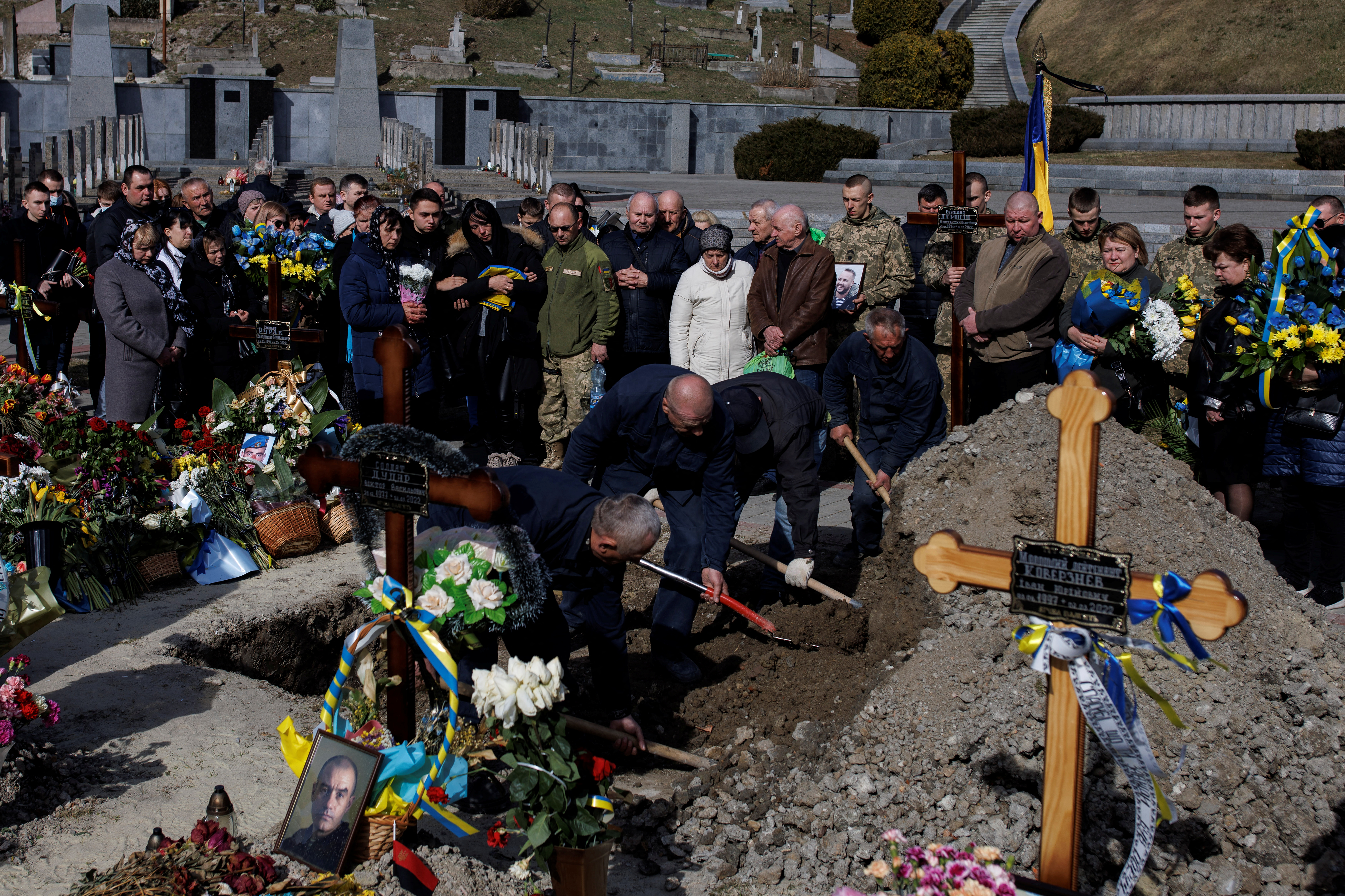 Cemetery workers cover the grave of sergeant Kostiantyn Deriuhin, who was killed in battle during Russia’s attack on Ukraine, during his funeral at the Lychakiv cemetery in Lviv