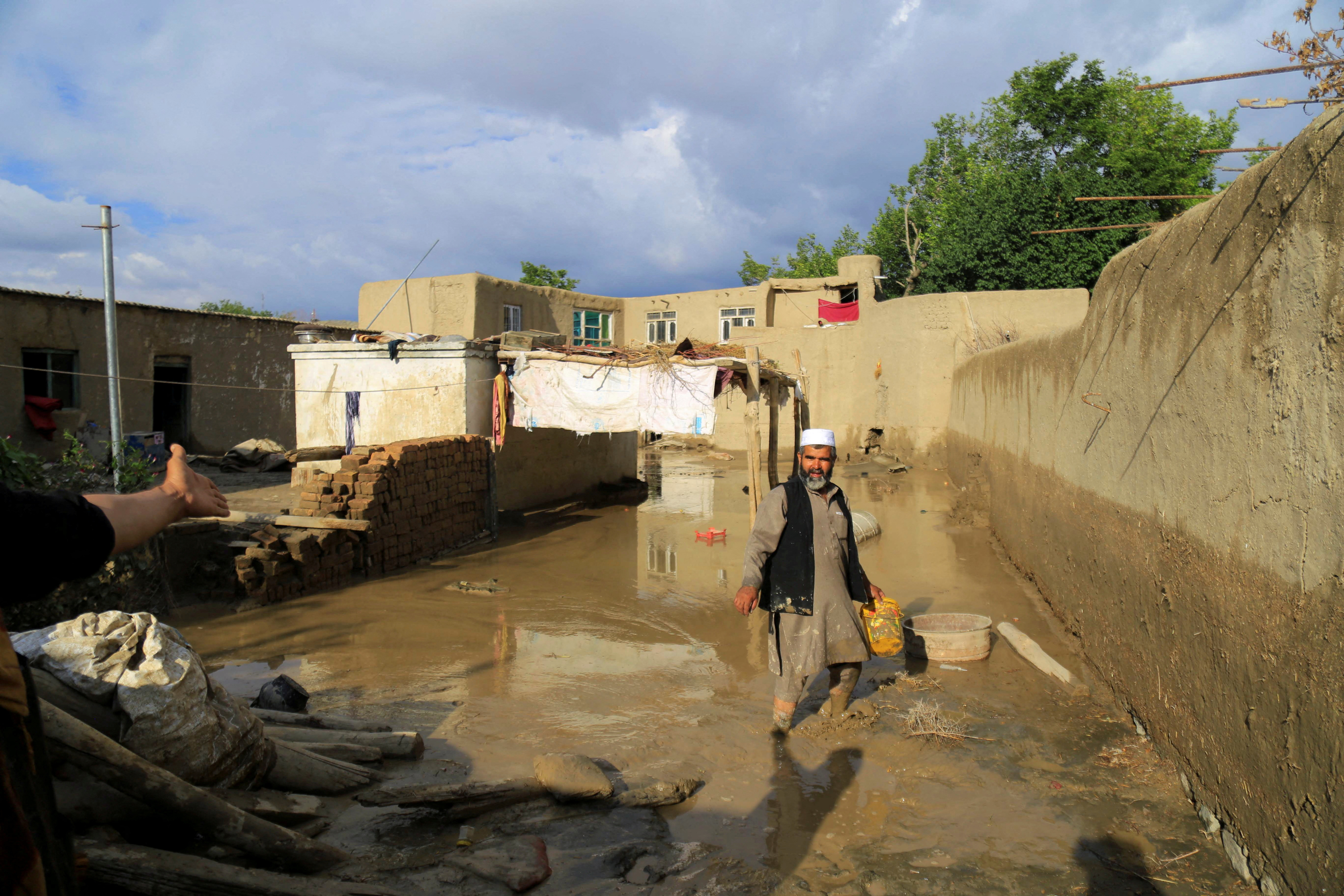 An Afghan man cleans up his damaged home after the heavy flood in the Khushi district of Logar