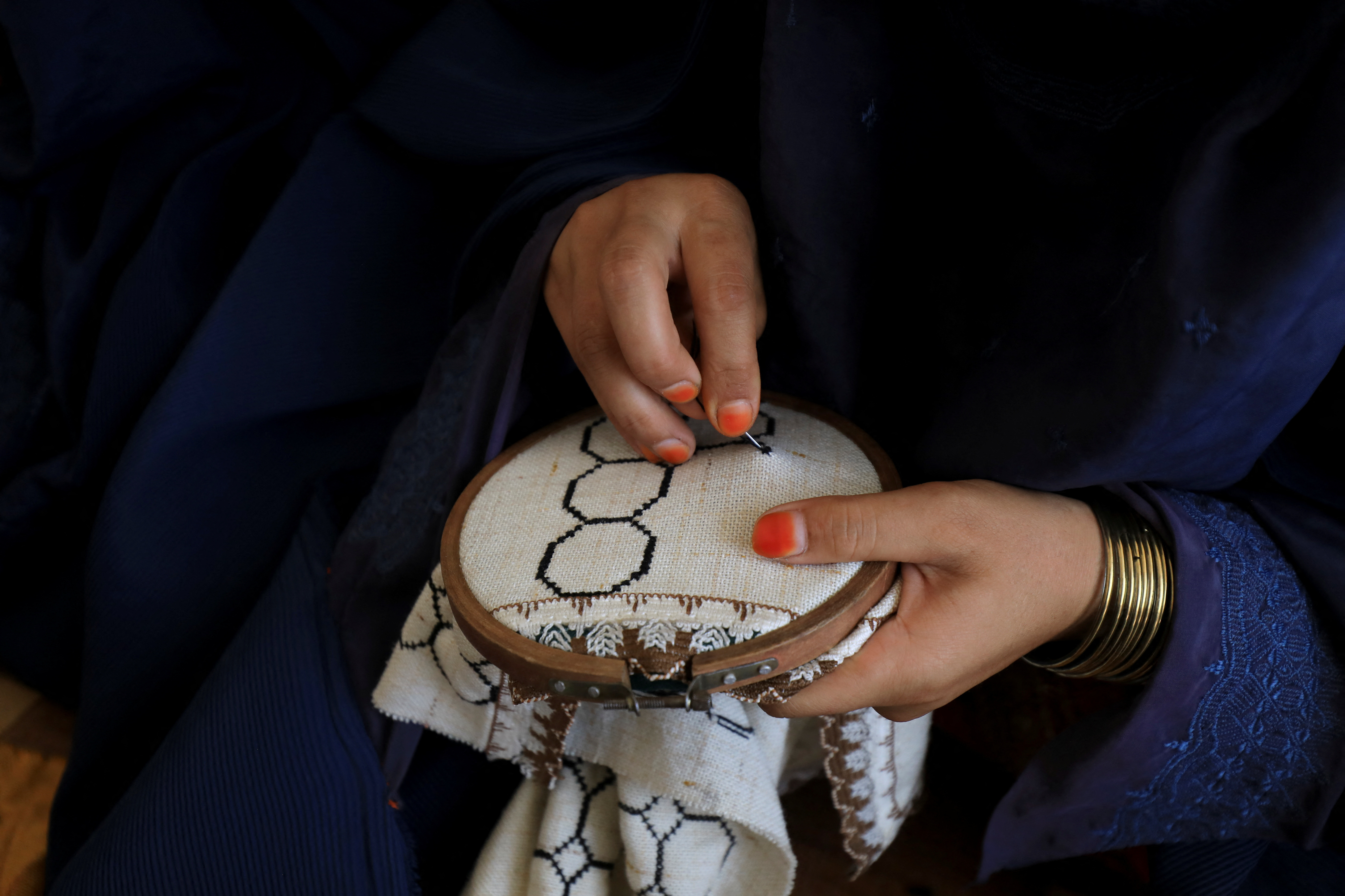 Afghan woman stitches fabric while attending tailoring class at the Skills Academy for Needy Aspirants, in Peshawar