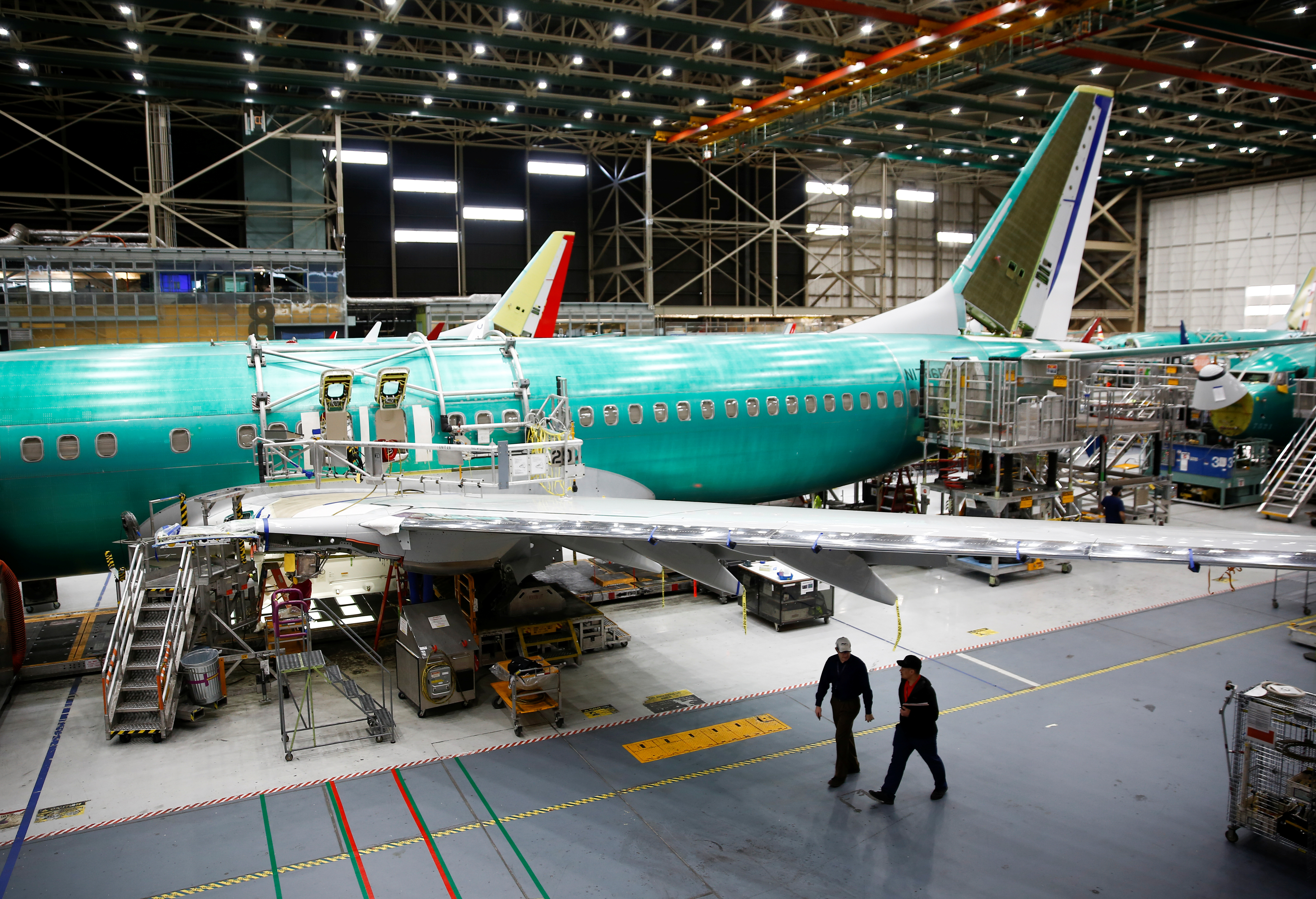 Two workers walk under the wing of a 737 Max aircraft at the Boeing factory in Renton