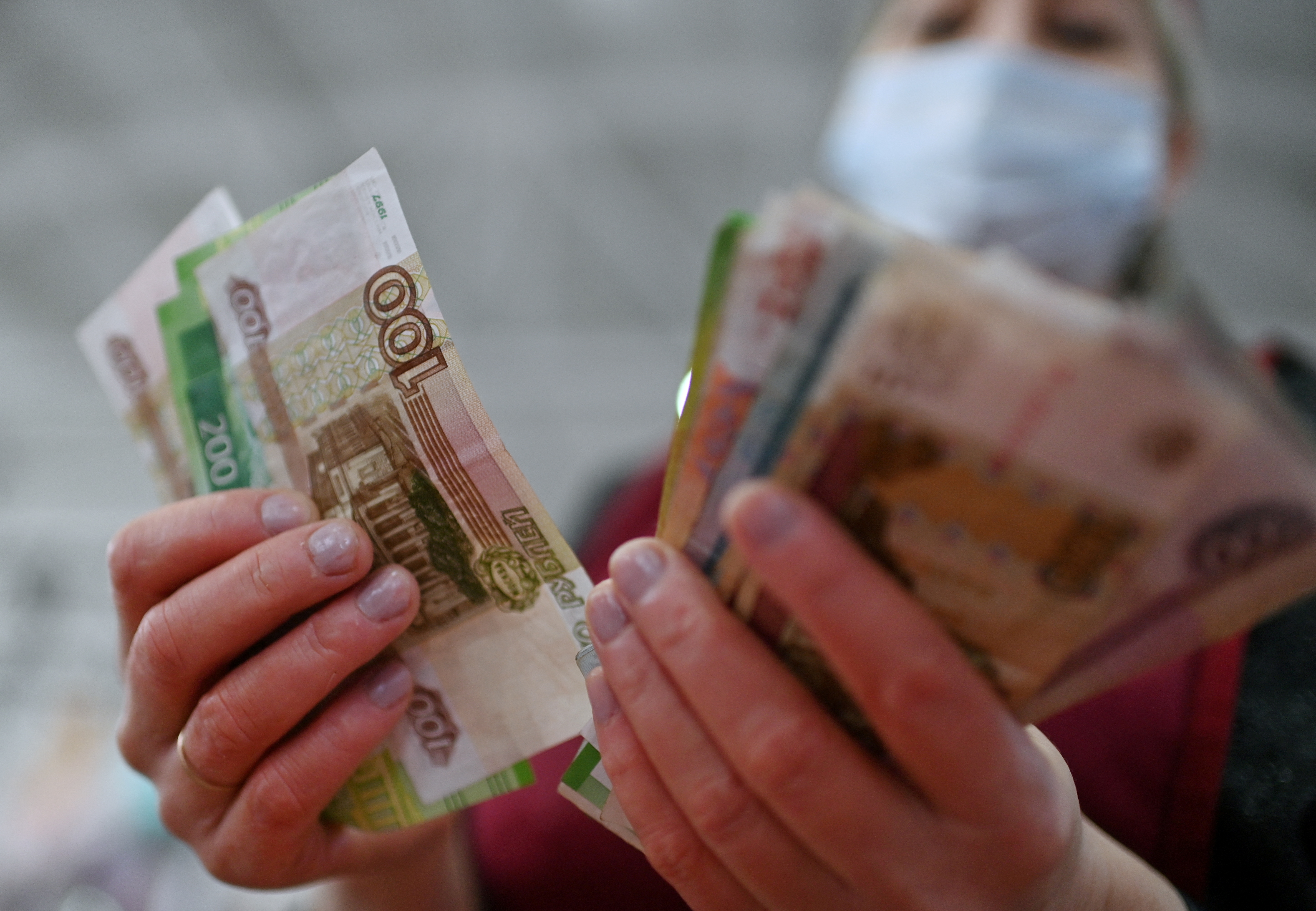 A vendor counts Russian rouble banknotes at a market in Omsk