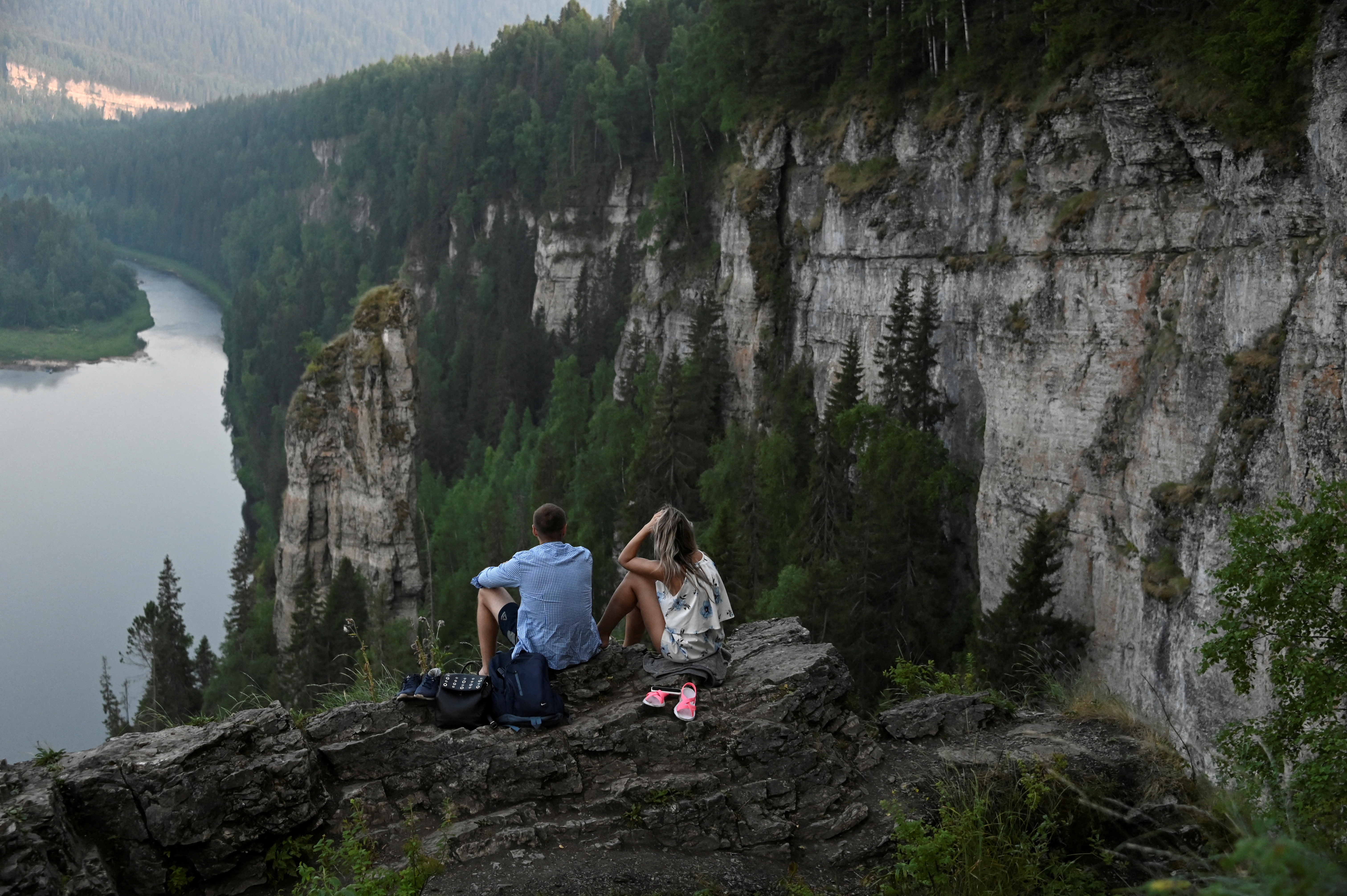 Tourists enjoy the view from stone pillars on the bank of the Usva River in Perm Region
