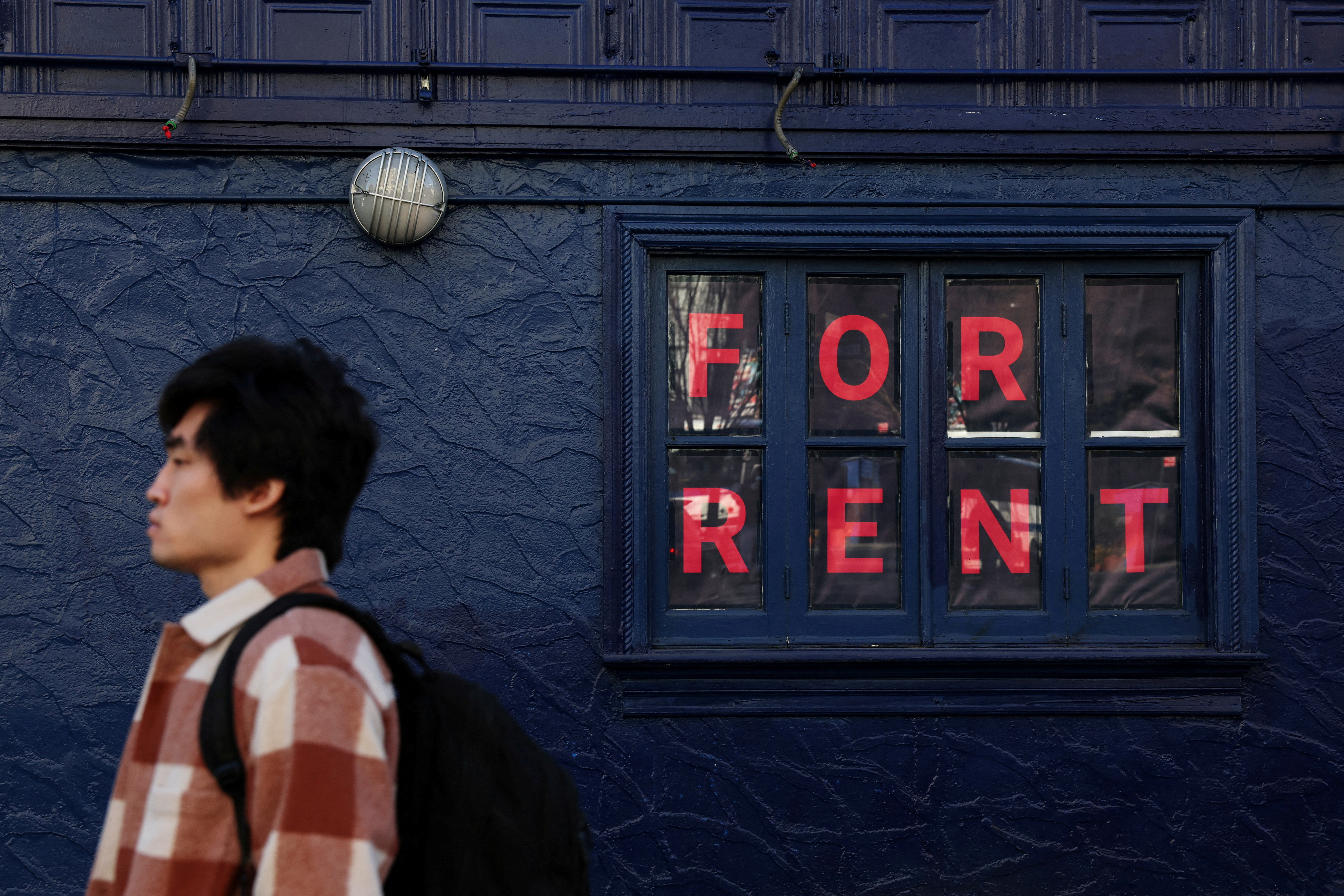 A man walks by as sign advertising real estate for rent in the SoHo area of New York City