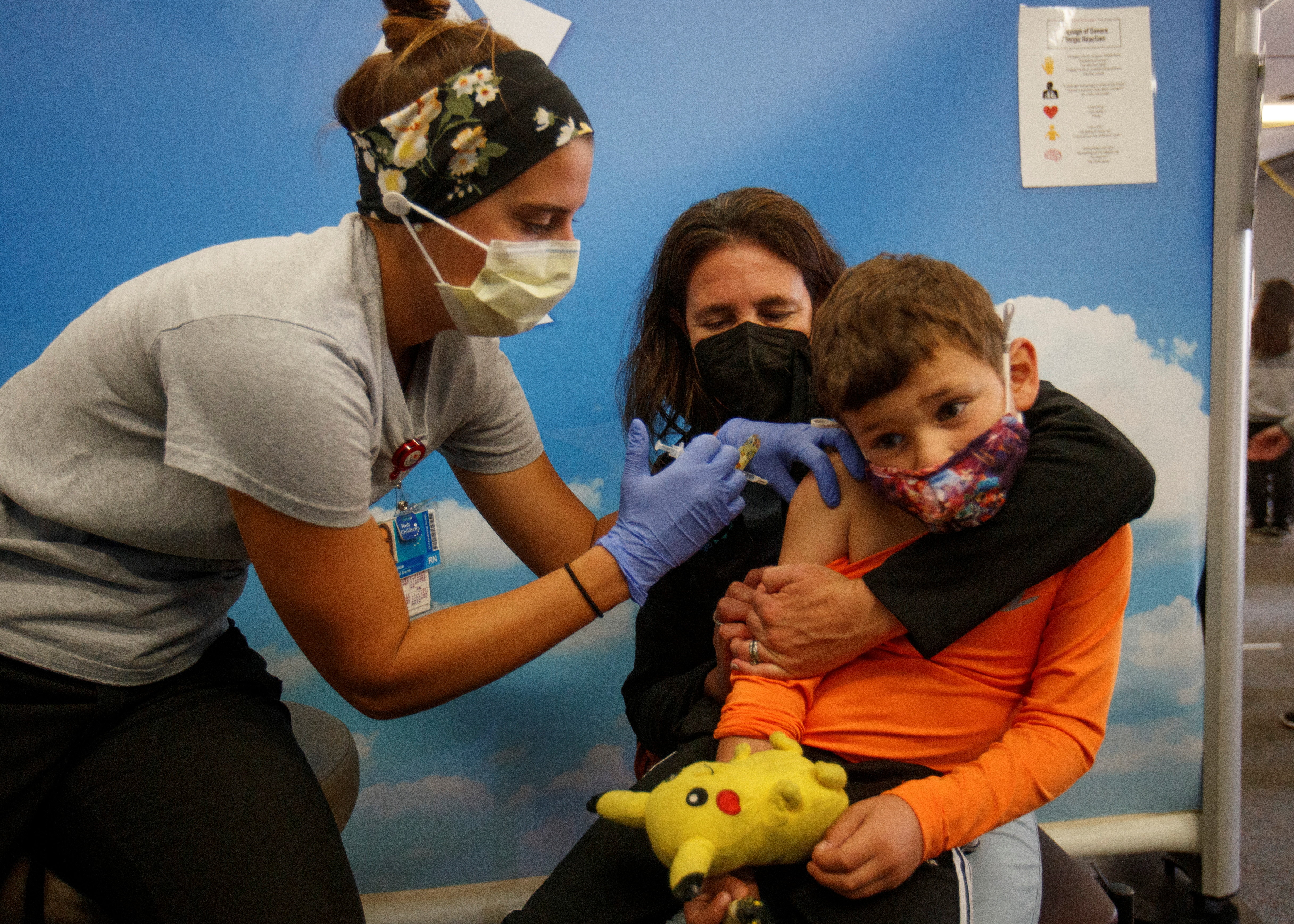 Five year-old Renan Rojas sits on his mom, Daniela Cantano's lap, as he receives the Pfizer-BioNTech coronavirus vaccine from registered nurse Jillian at Rady's Children's hospital vaccination clinic in San Diego, California, U.S., November 3, 2021.  REUTERS/Mike Blake