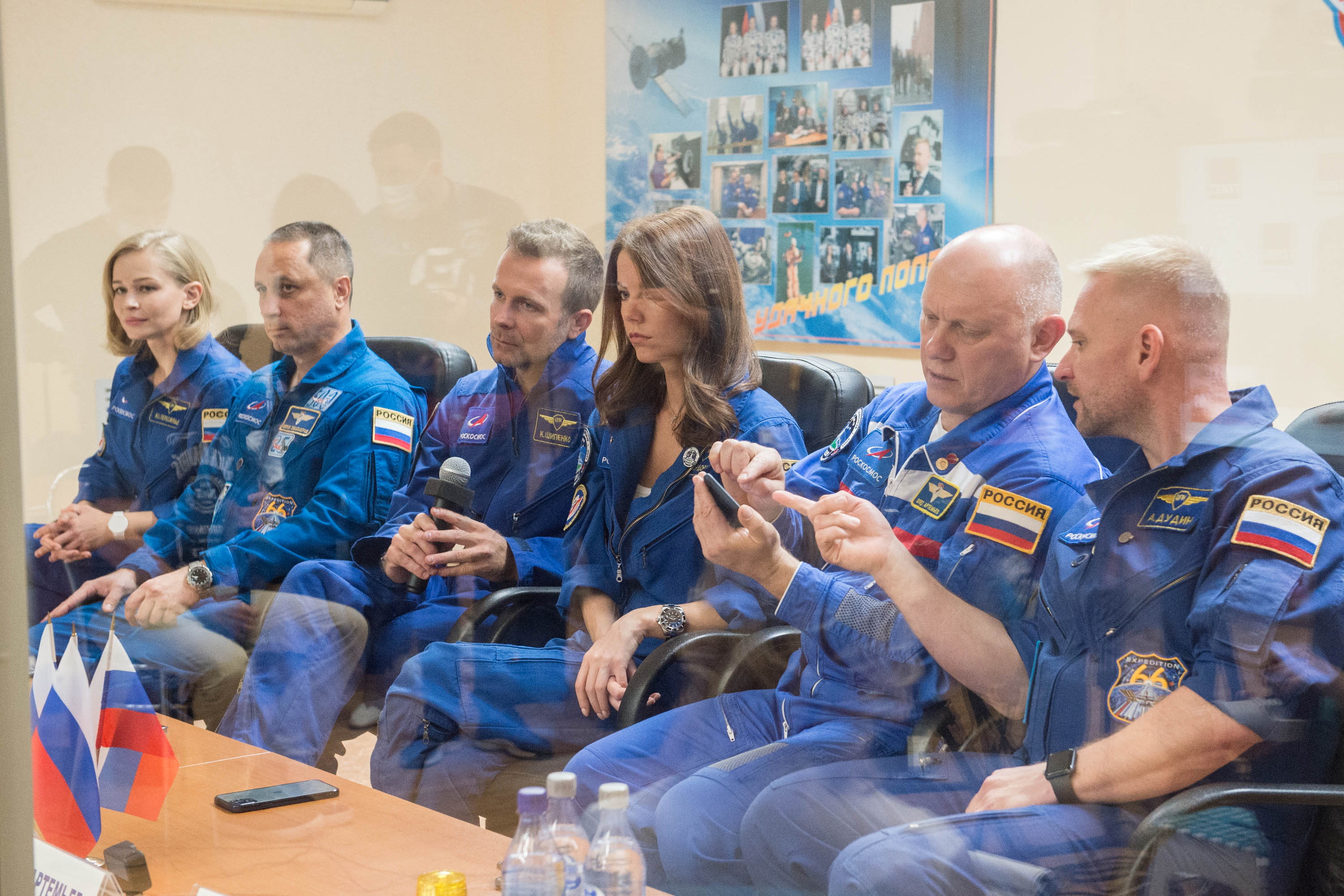 Crew members, Anton Shkaplerov, Yulia Peresild and Klim Shipenko, and back-up crew members, Oleg Artemyev, Alyona Mordovina and Alexei Dudin, sit behind a glass wall during a news conference ahead of the expedition to the International Space Station (ISS) at the Baikonur Cosmodrome, Kazakhstan October 4, 2021. The launch is scheduled for October 5, 2021. Andrey Shelepin/GCTC/Roscosmos/Handout via REUTERS  