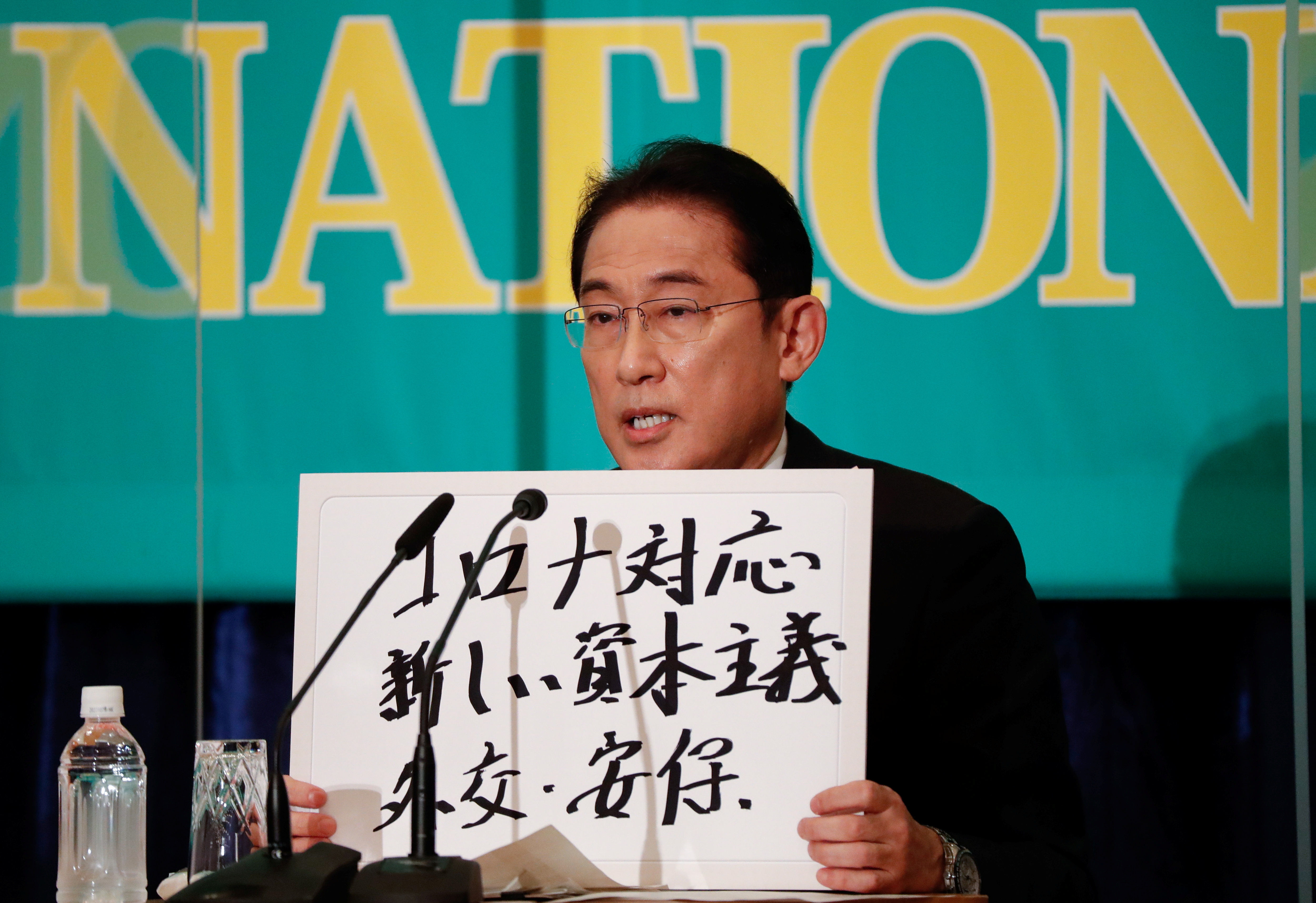 Japan's Prime Minister Fumio Kishida, who is also ruling Liberal Democratic Party President, holds up a placard reading 
