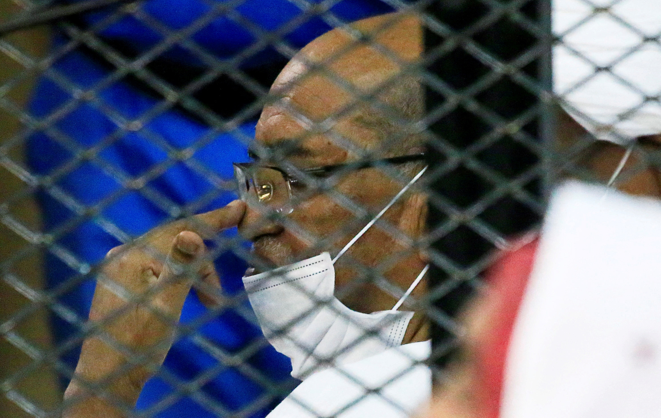 Sudan's ousted President Omar al-Bashir is seen inside the defendant's cage during his and some of his former allies trial over the 1989 military coup that brought the autocrat to power in 1989, at a courthouse in Khartoum