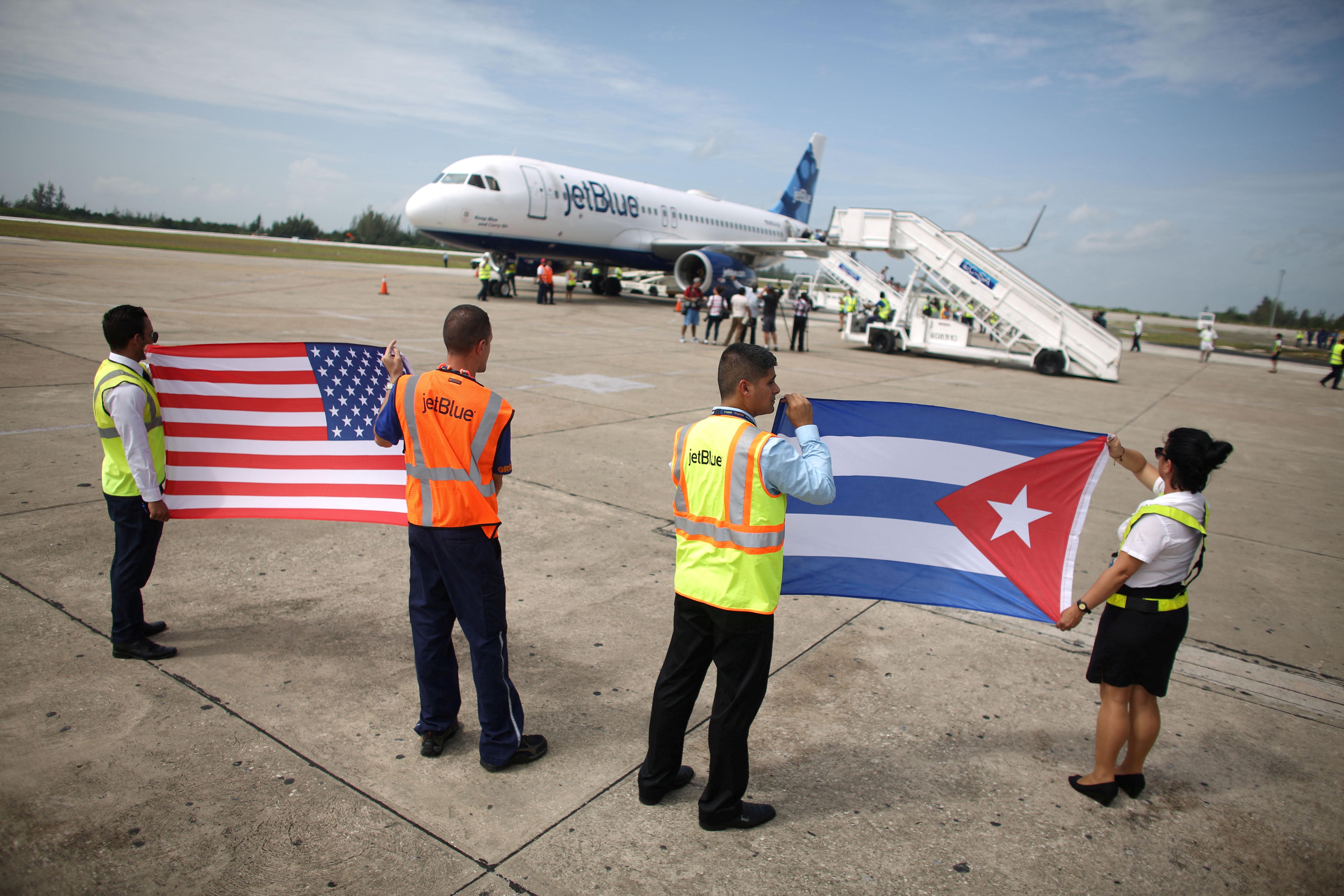Ground crew hold U.S. and Cuban flags near a recently landed JetBlue aeroplane at the Abel Santamaria International Airport in Santa Clara