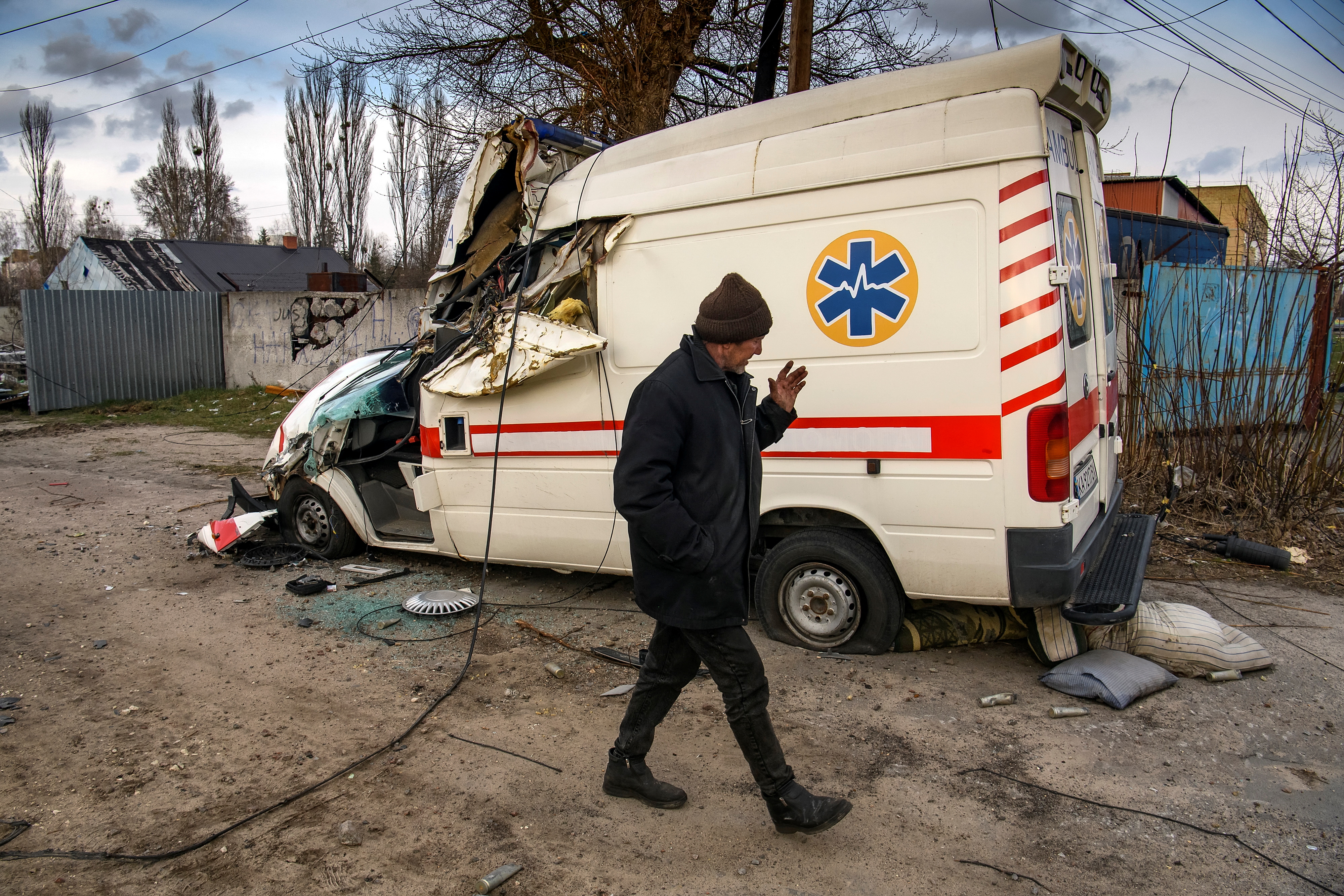 A local man walks past a damaged ambulance in the settlement of Hostomel