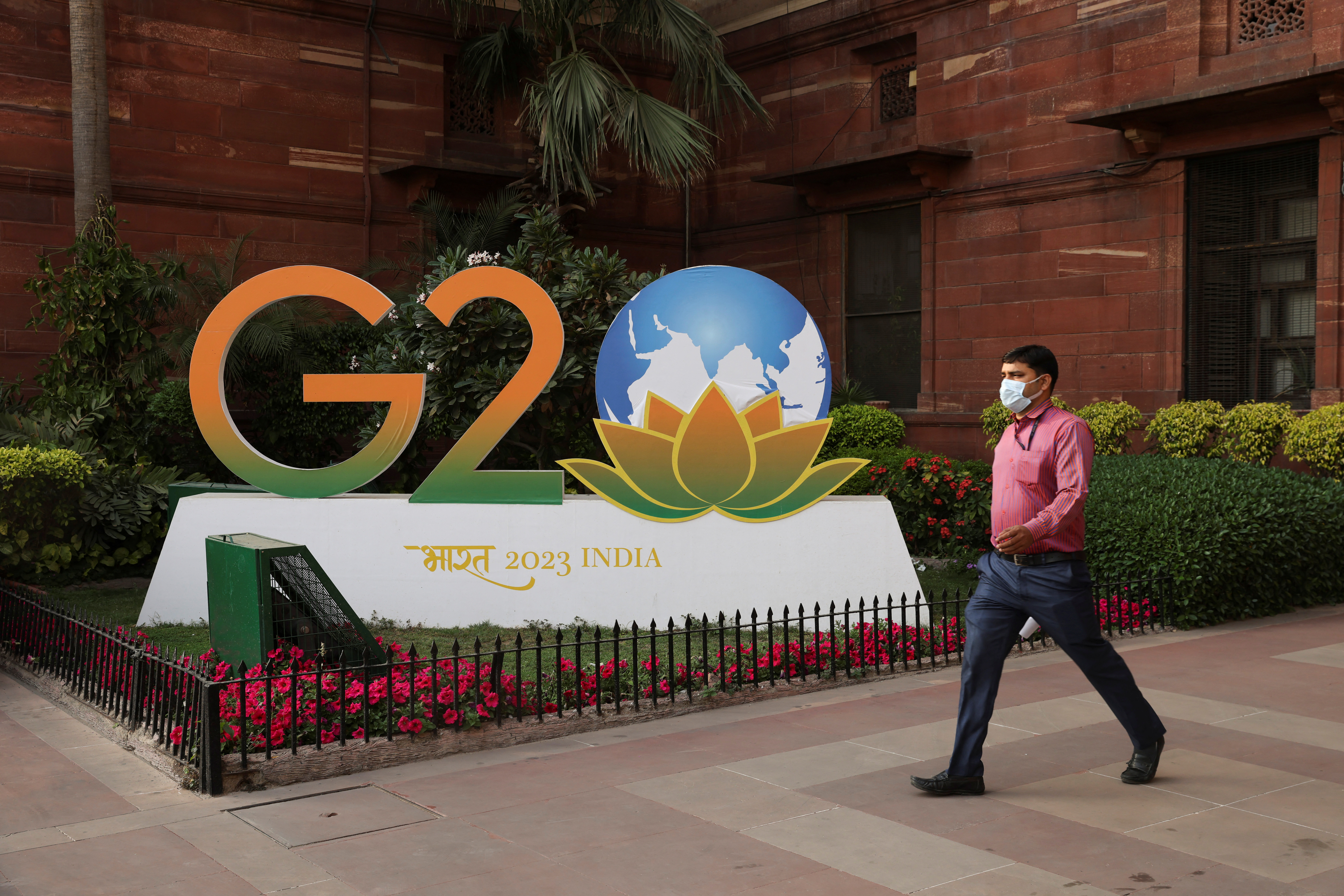 A man walks past a model of G20 logo outside the finance ministry in New Delhi