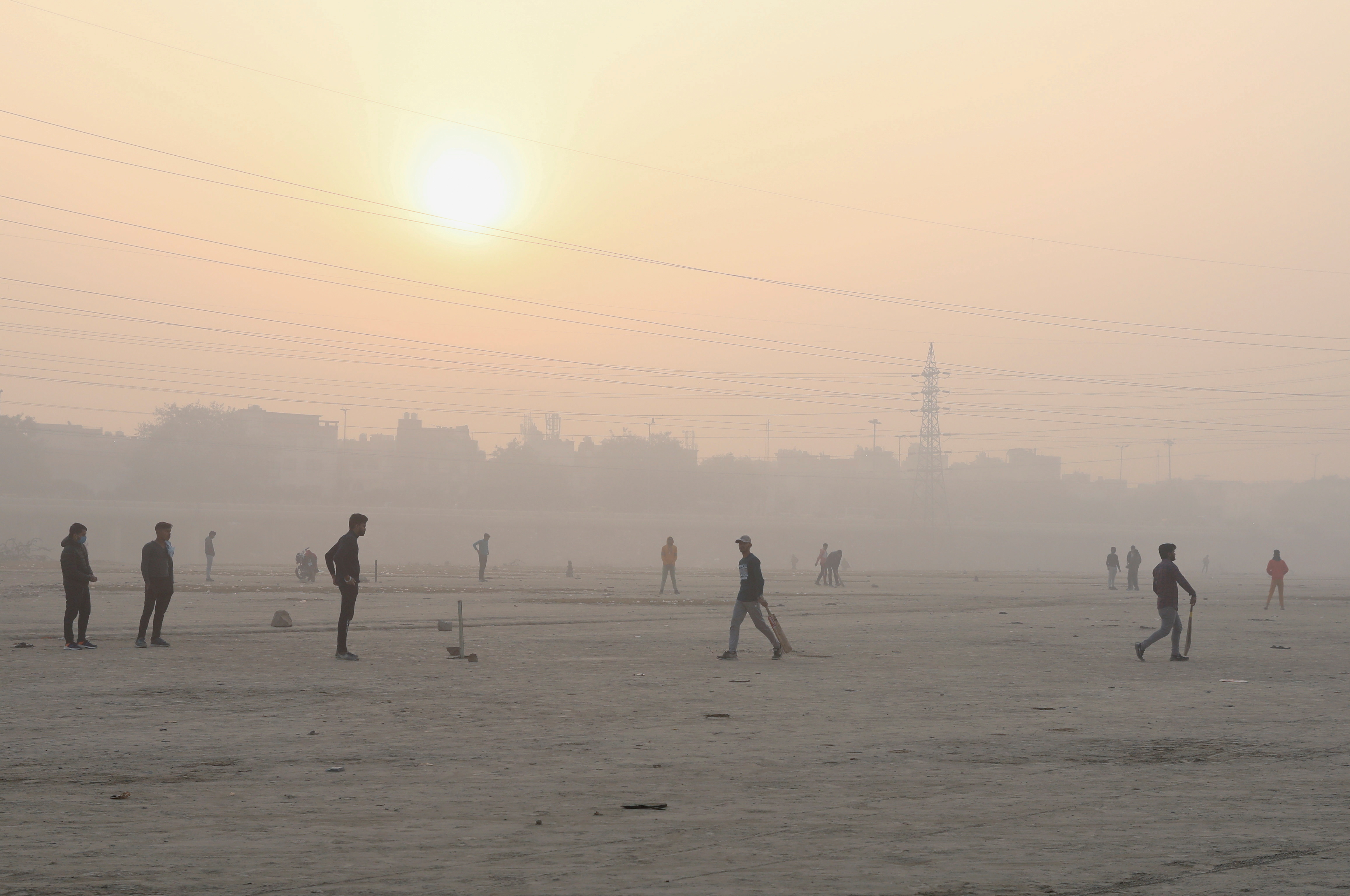 People play cricket on the floodplains of the Yamuna river on a smoggy morning in New Delhi, India, November 17, 2021. REUTERS/Anushree Fadnavis