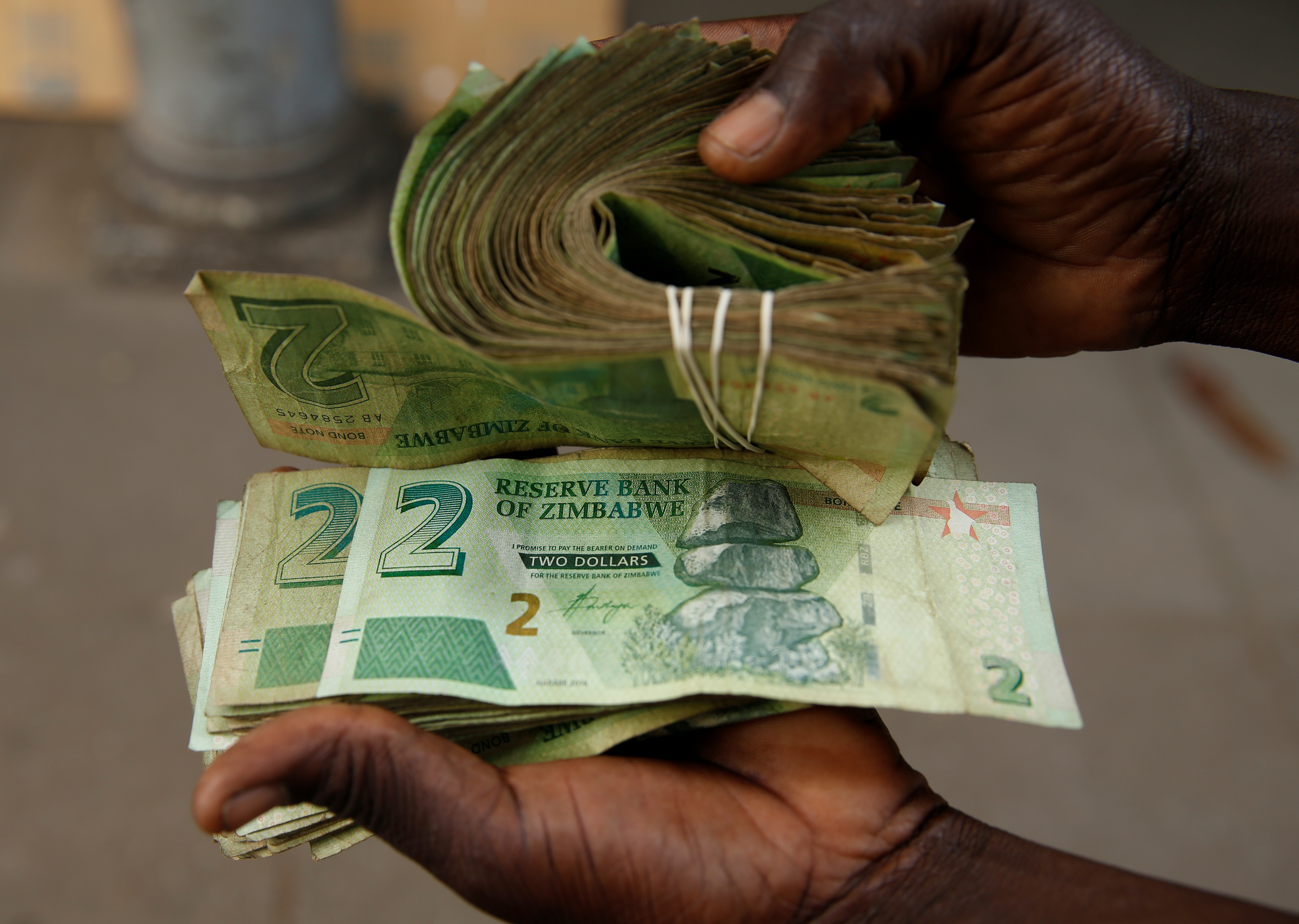 A street vendor poses as he displays bond notes, before the introduction of new currency in Harare