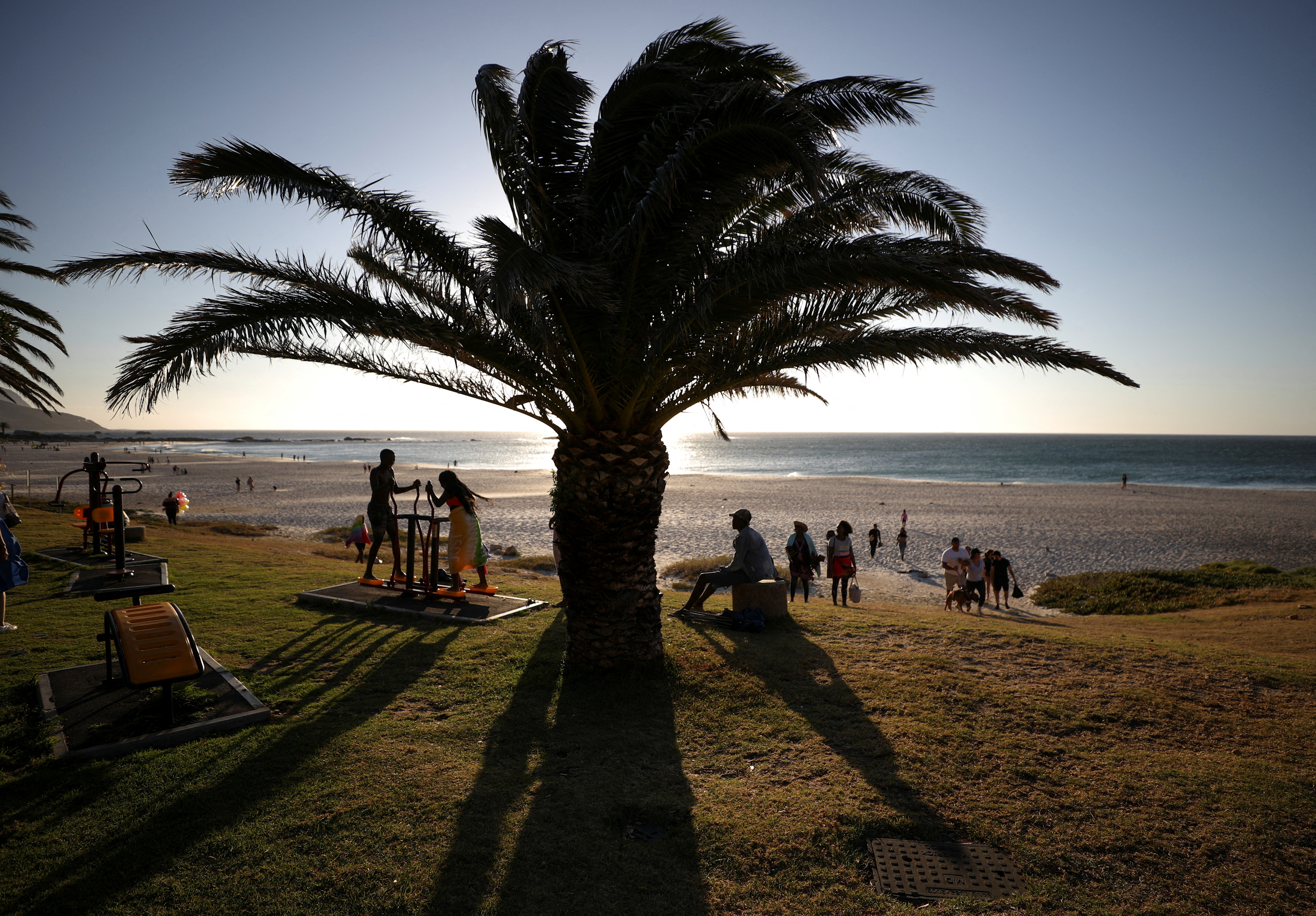 Vistors take in the sunlight at Camps Bay beach in Cape Town