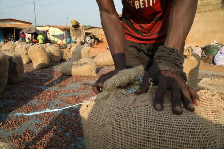 Workers sew up sacks of cocoa next to a warehouse in Soubre,