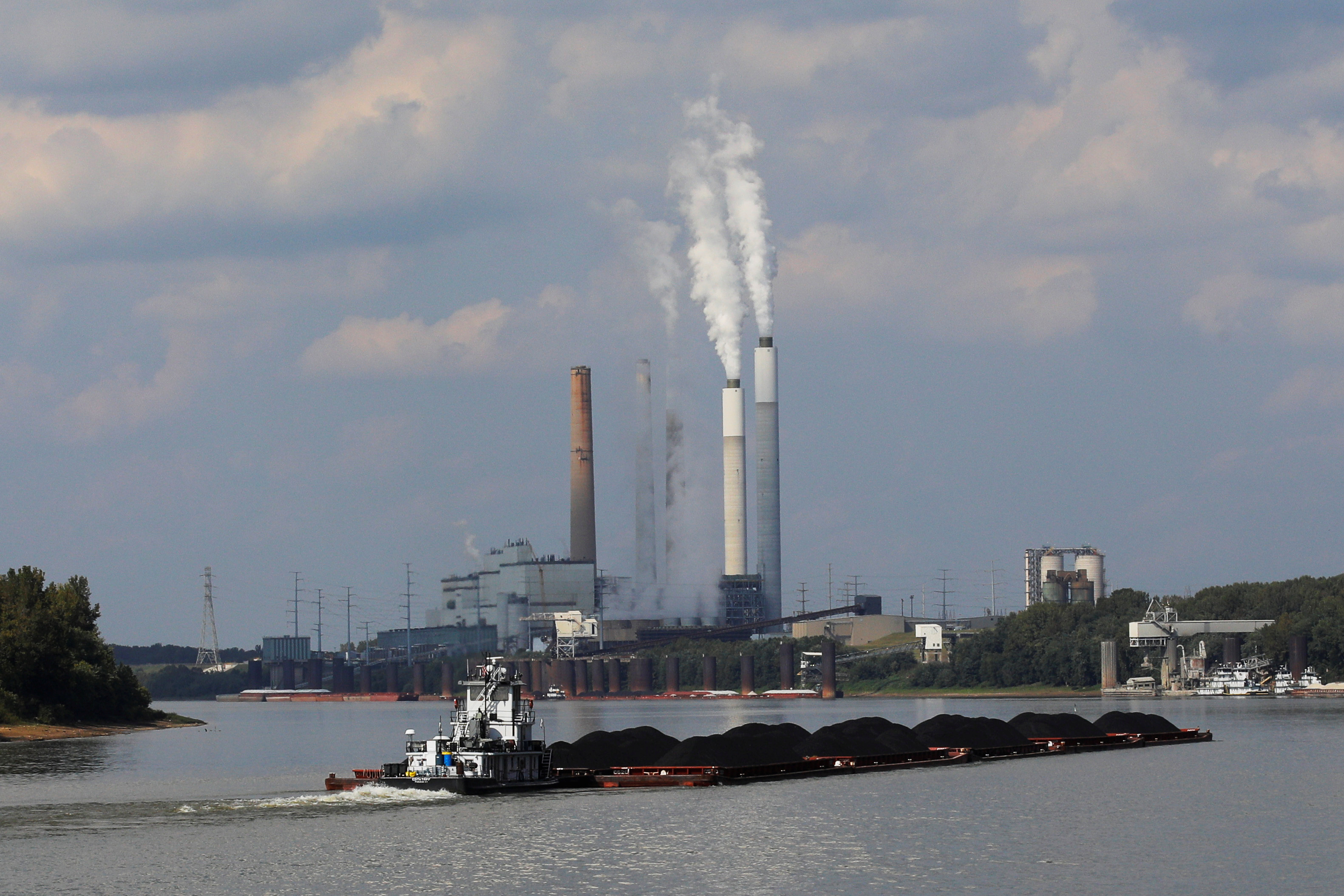 A towboat pushes barges towards the Mill Creek Station power plant on the Ohio River in Louisville